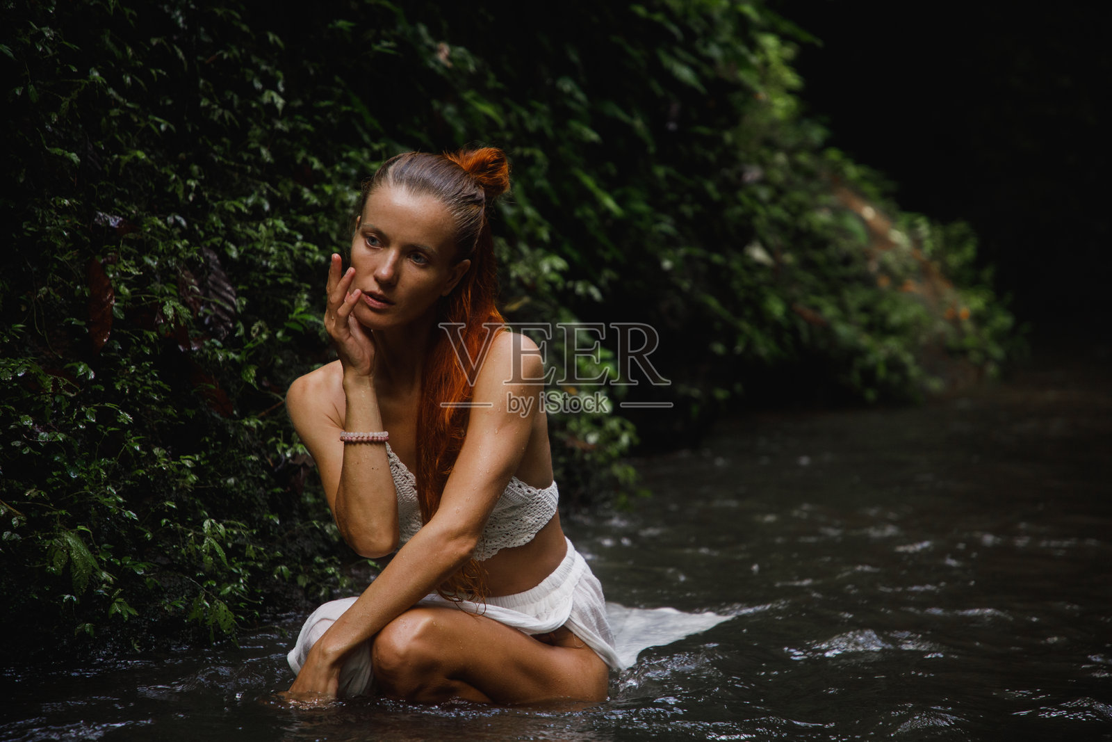 年轻女性在郁郁葱葱的绿意和流动的水边宁静的环境中照片摄影图片