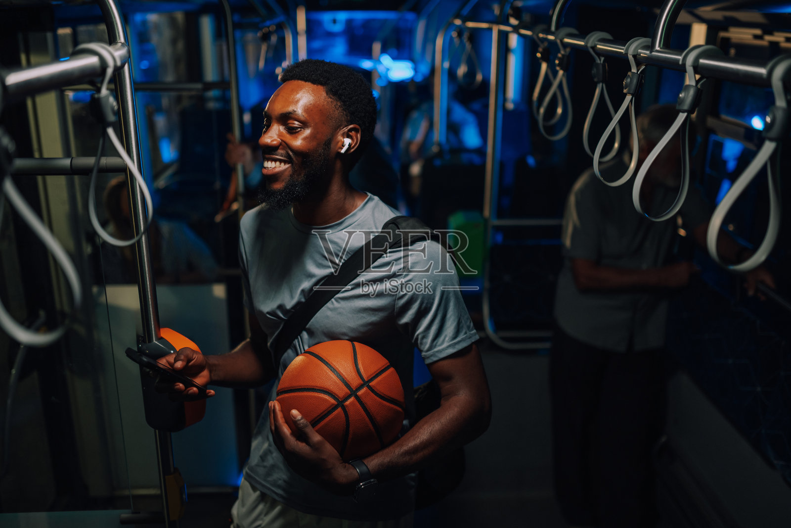 年轻的篮球运动员在公交车上微笑着听音乐照片摄影图片