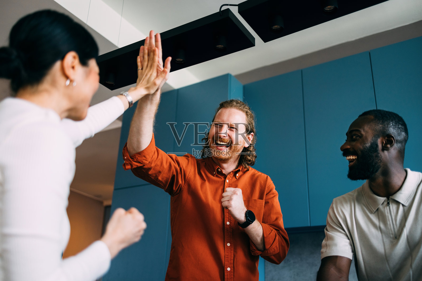 一群朋友在现代房间里庆祝成功，击掌相庆照片摄影图片