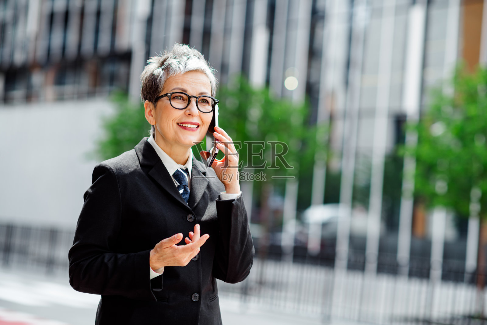 自信的成熟的女商人短发微笑着在城市户外用手机通话照片摄影图片