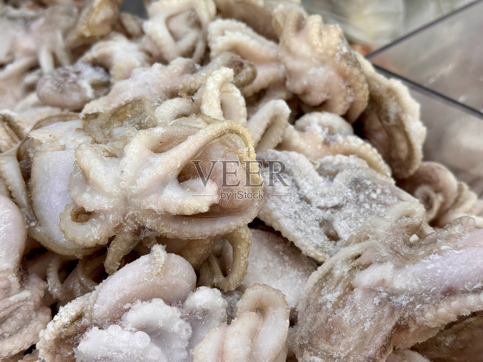 享受美味的冷冻海鲜拼盘，包含小章鱼和各种头足类动物。细致的特写镜头展示冷冻小章鱼，突显其独特的形状和纹理。照片摄影图片