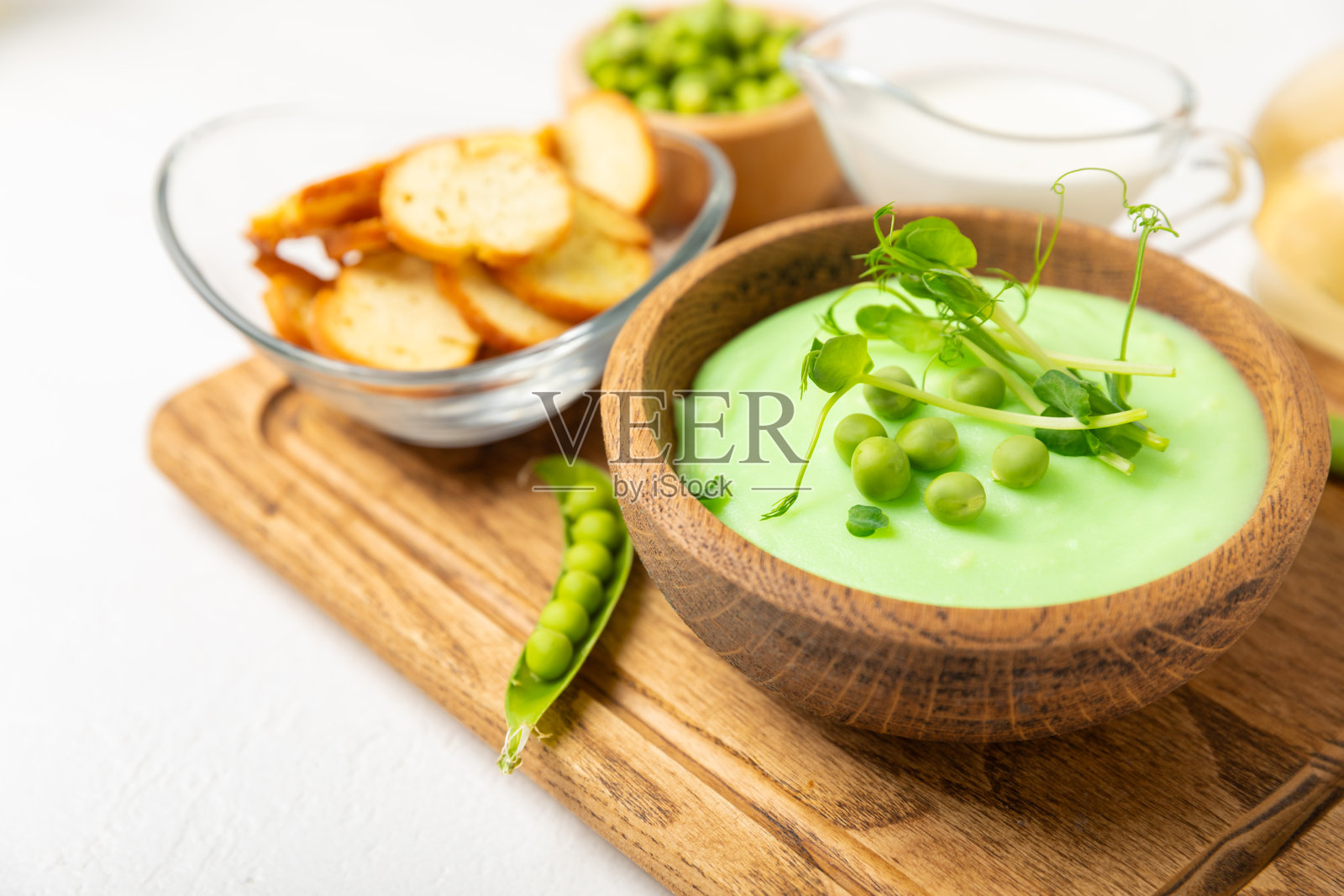 木桌上的青豆汤。新鲜的青豆汤碗。美味健康的奶油汤，碗中有青豆和面包丁。健康的素食泥。留白。文本空间。照片摄影图片