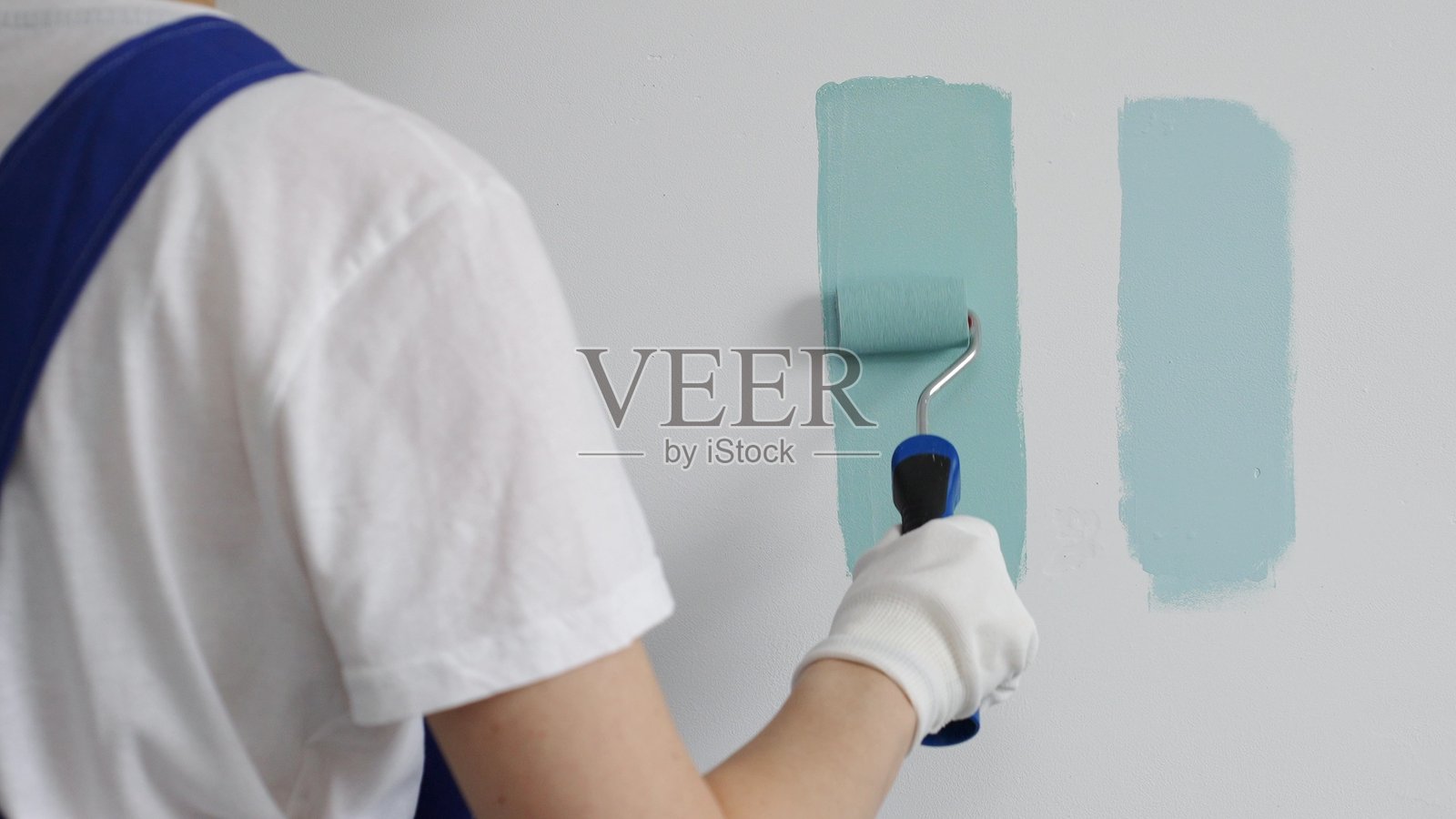 专业画家手持滚筒，比较浅绿色涂料的色调，选择家居装修的精确墙面颜色，确保理想的室内设计美学照片摄影图片