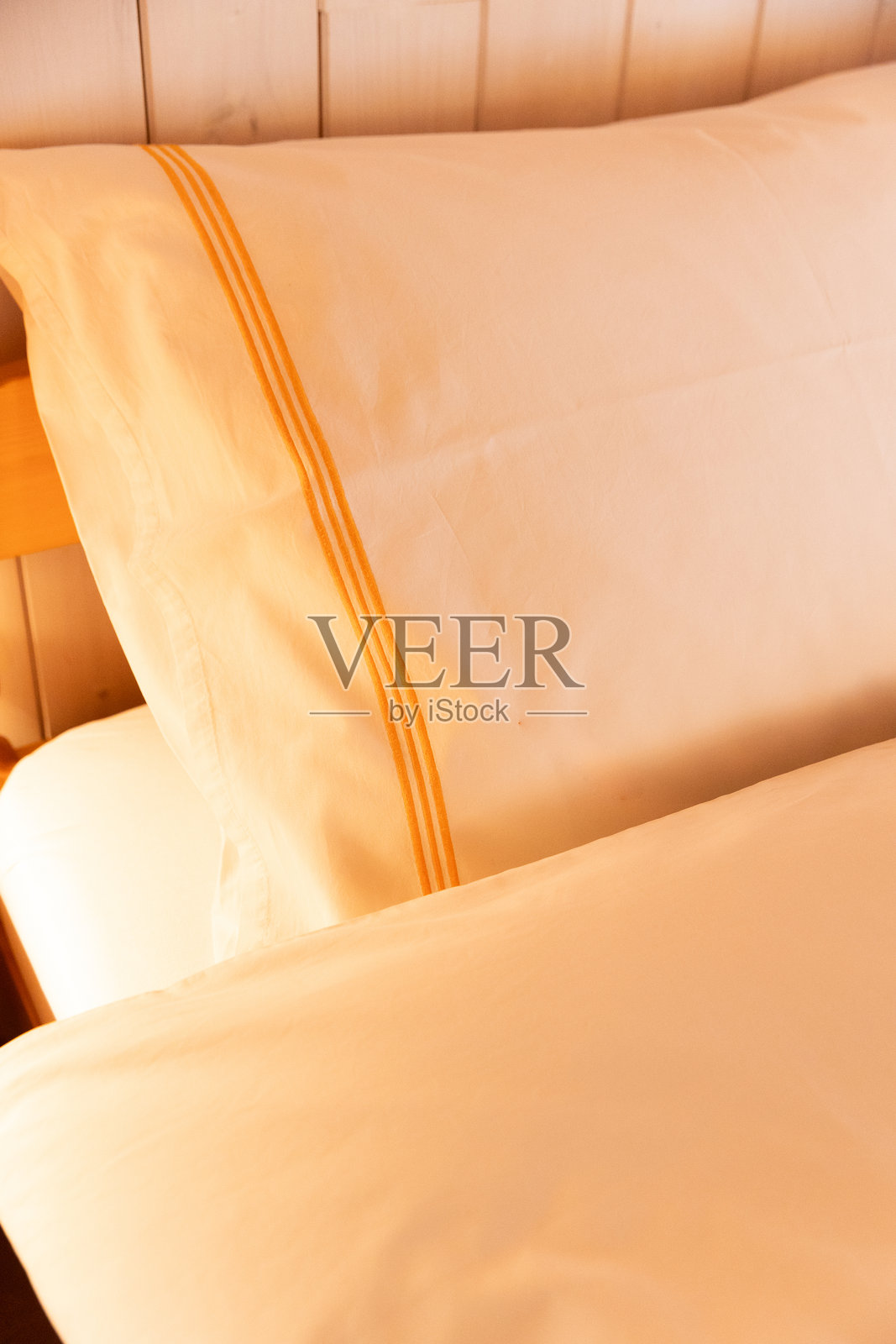 床的细节，几乎只能看到被红黄光照亮的枕头。非常舒适。照片摄影图片