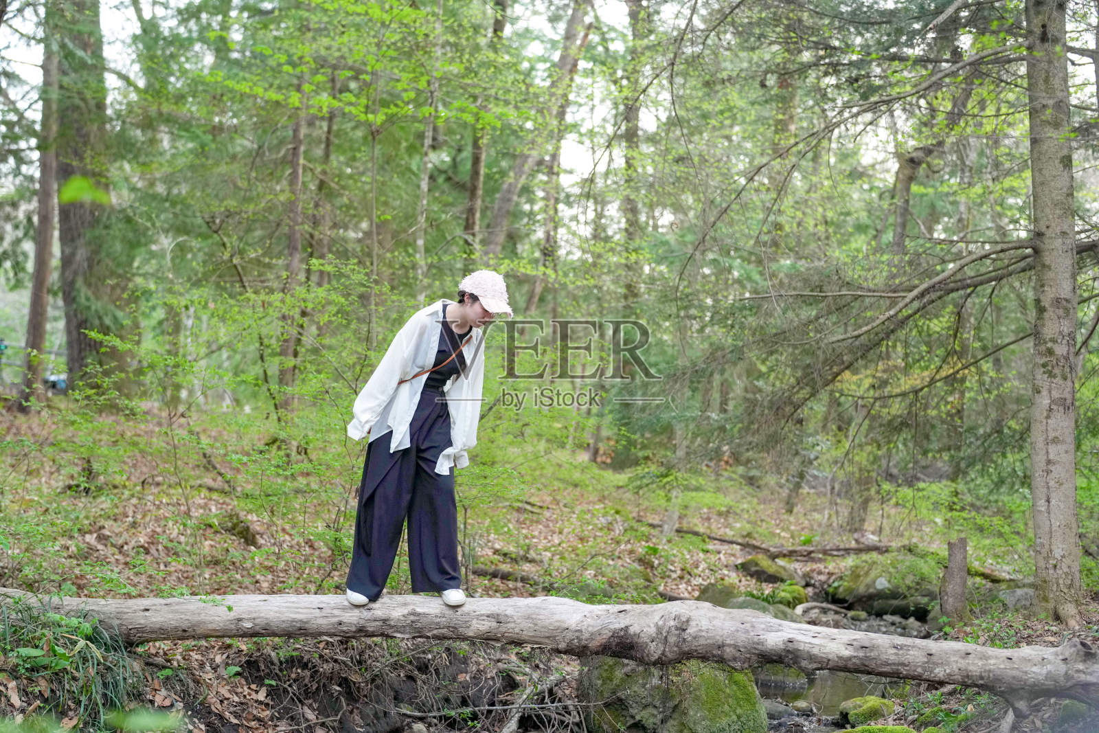 一位女性站在森林中的一根树干上照片摄影图片