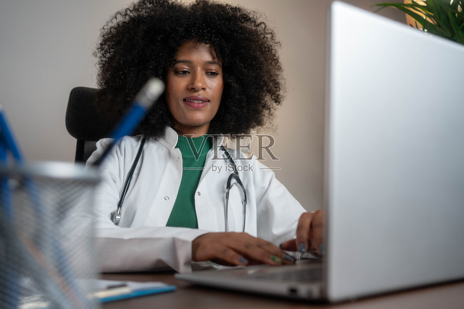 非洲女性医生在医疗办公室使用笔记本电脑，专注且自信的专业人士照片摄影图片