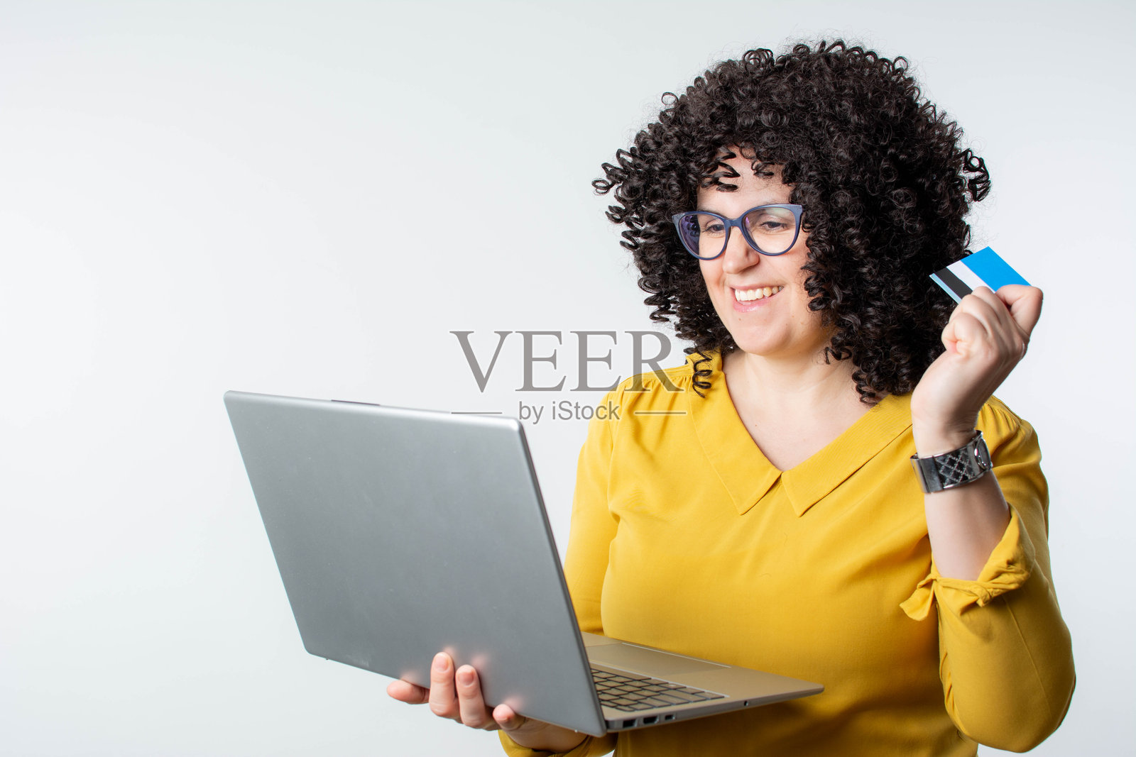 快乐的卷发女性在笔记本电脑上用信用卡购物照片摄影图片