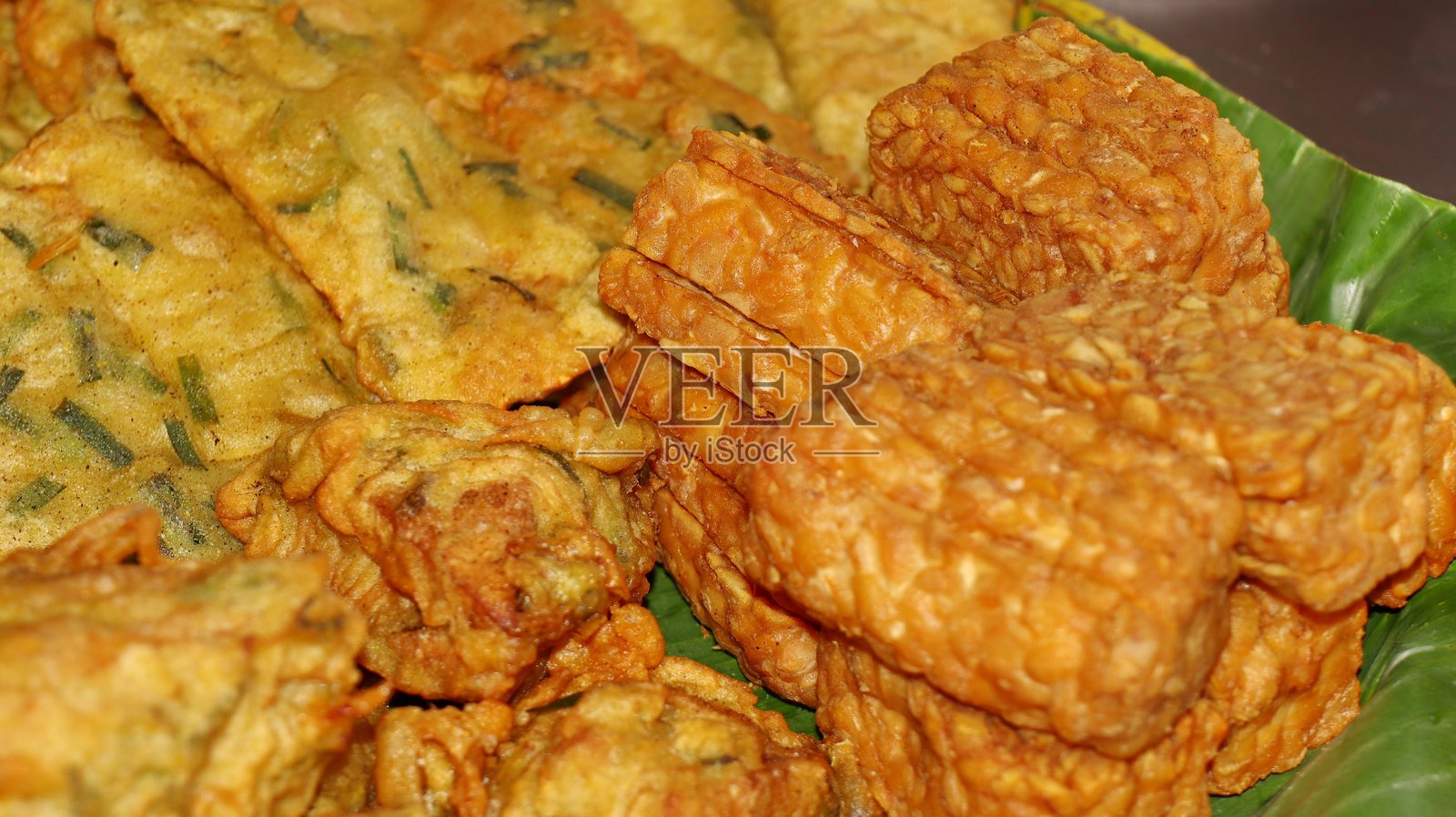 印尼炸小吃拼盘，包括天贝、油炸饼和豆腐，盛放在传统盘子上照片摄影图片