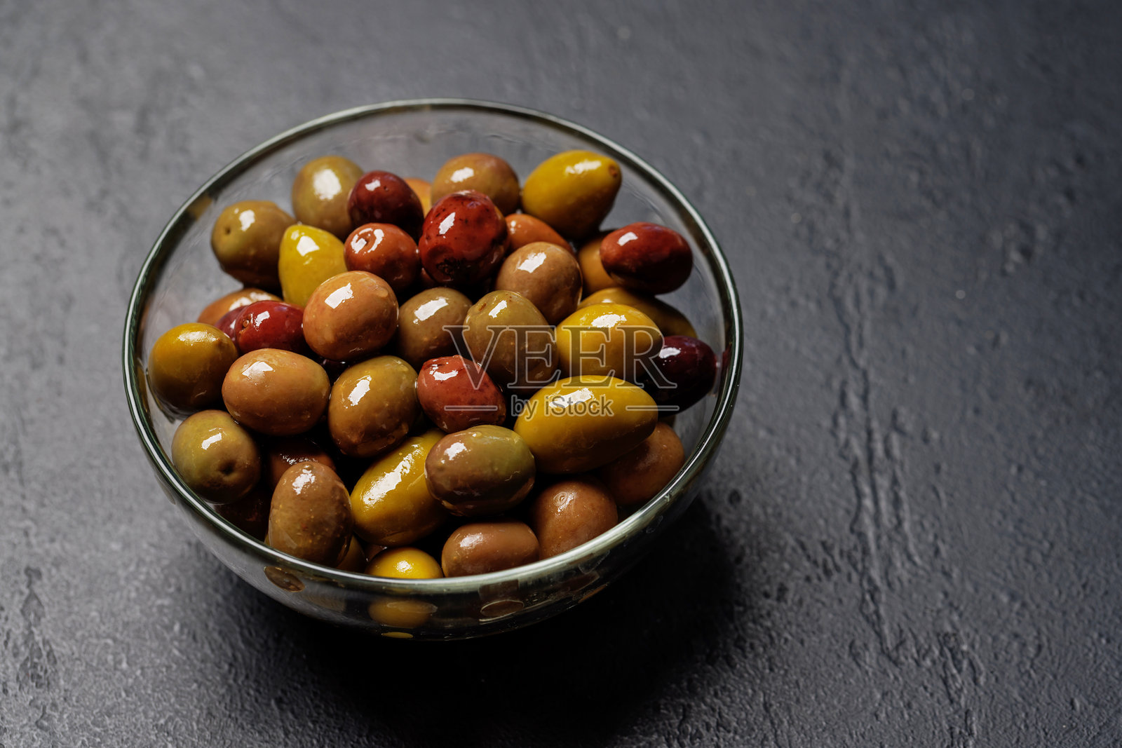 一碗盛放各种橄榄的拼盘，展示了不同的颜色、质地和风味。照片摄影图片
