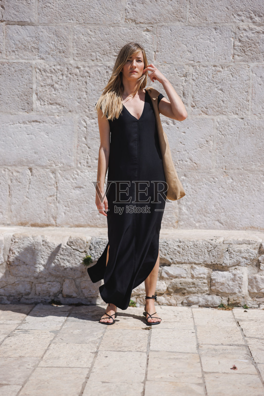 穿着黑色连衣裙的女人在阳光明媚的日子里户外散步照片摄影图片