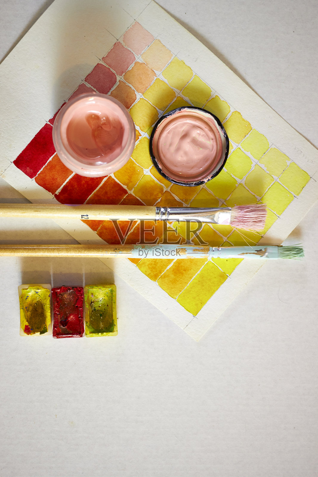 创意平铺，包含水彩颜料、画笔、调色板和纸上的色卡。适用于设计、创意、手工艺和艺术概念背景的艺术构图。照片摄影图片