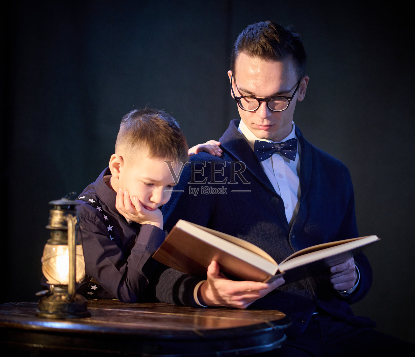 聪明的年轻人正在给弟弟读一本聪明的书照片摄影图片