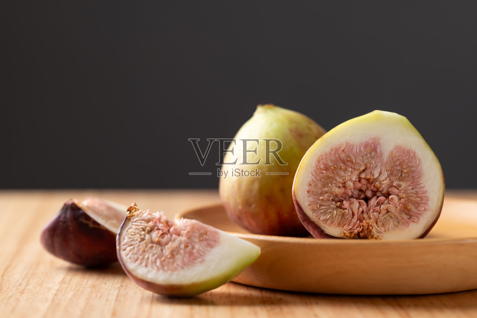新鲜无花果放在木盘上，背景为黑色照片摄影图片