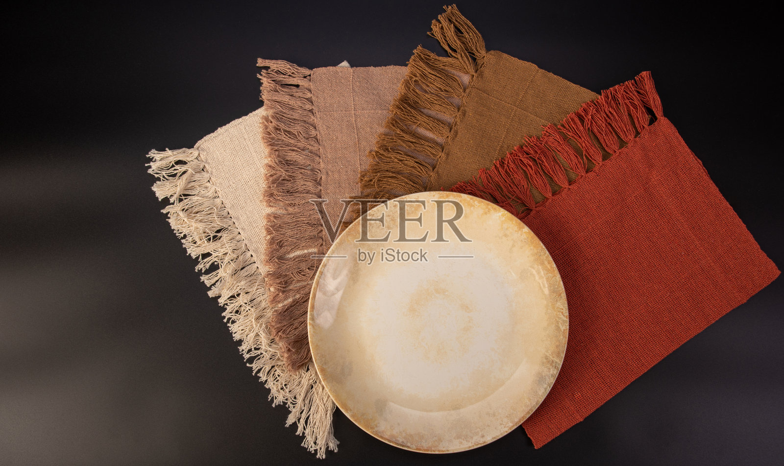 美丽的餐桌布置，精美的盘子、餐具和餐巾放置在深色背景上，选择性对焦。照片摄影图片