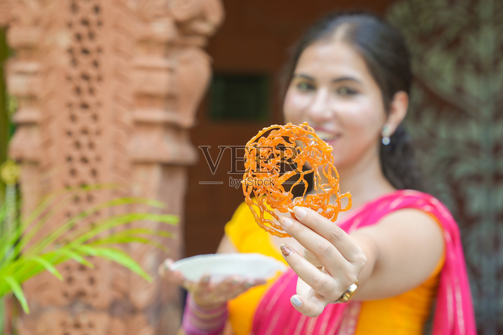 年轻美丽的印度女性享受吃印度甜点贾雷比。糖果甜点。印度美食。选择性聚焦。照片摄影图片