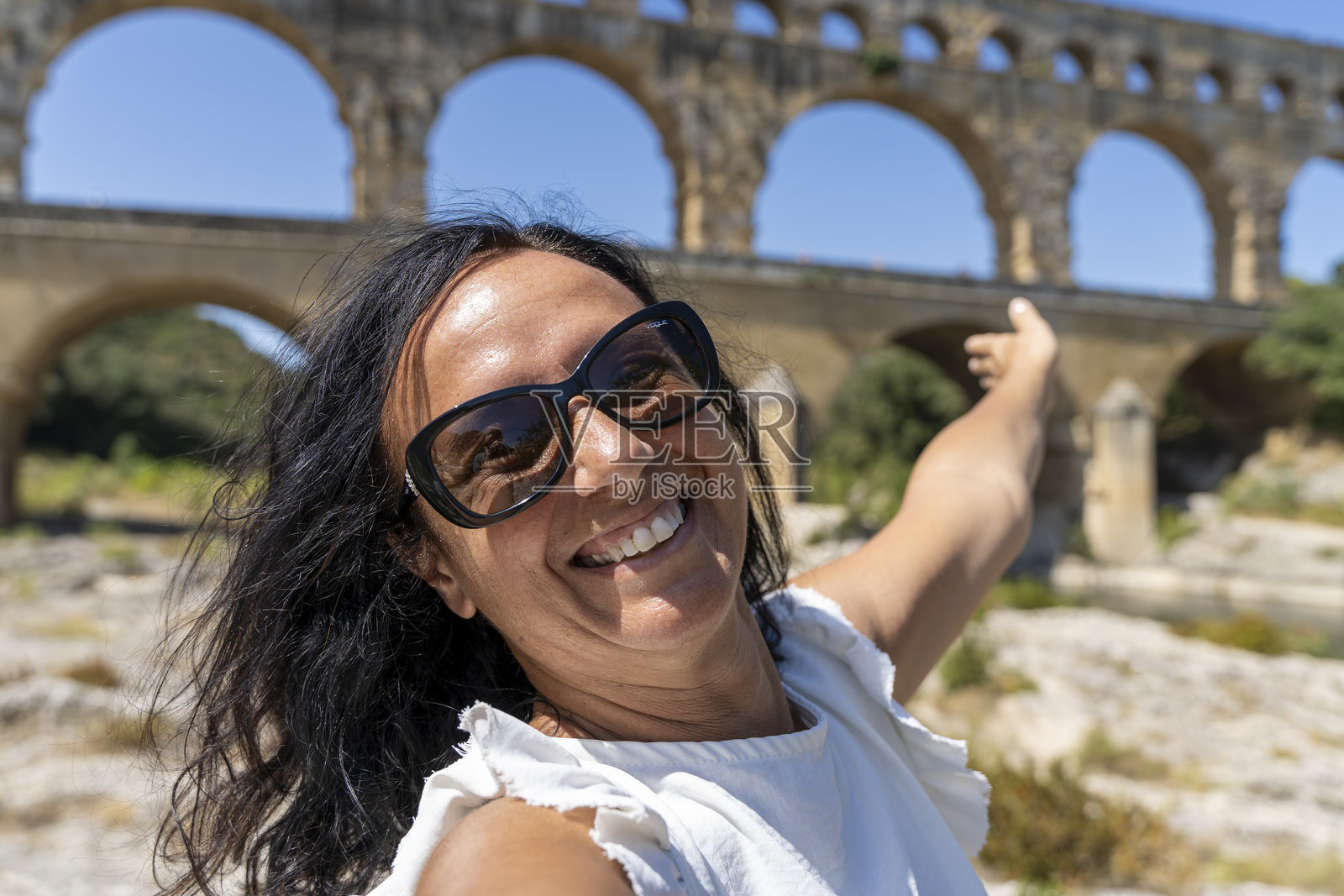 美丽的成熟退休女性旅行者在法国的罗马高架水渠庞特·迪加尔前自拍照片摄影图片