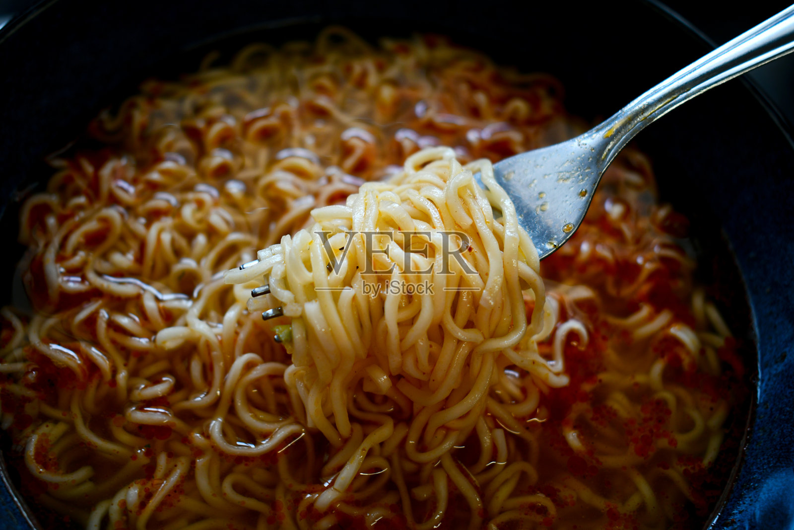 碗里的方便面和叉子。吃面汤。照片摄影图片