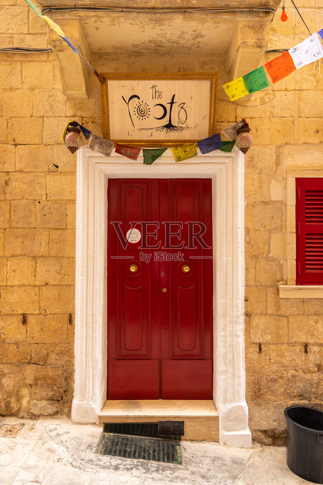 马耳他瓦莱塔的红色门，门上挂着标志和祈祷旗。照片摄影图片