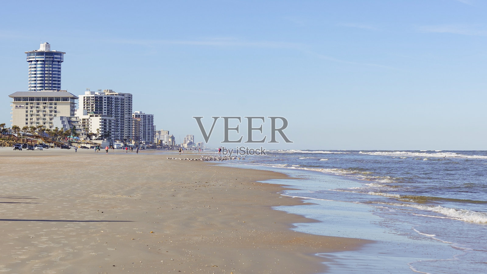 风景如画的海滩景观，沿海建筑、温柔的海浪和湛蓝的天空，位于一个充满活力的海滨地点照片摄影图片