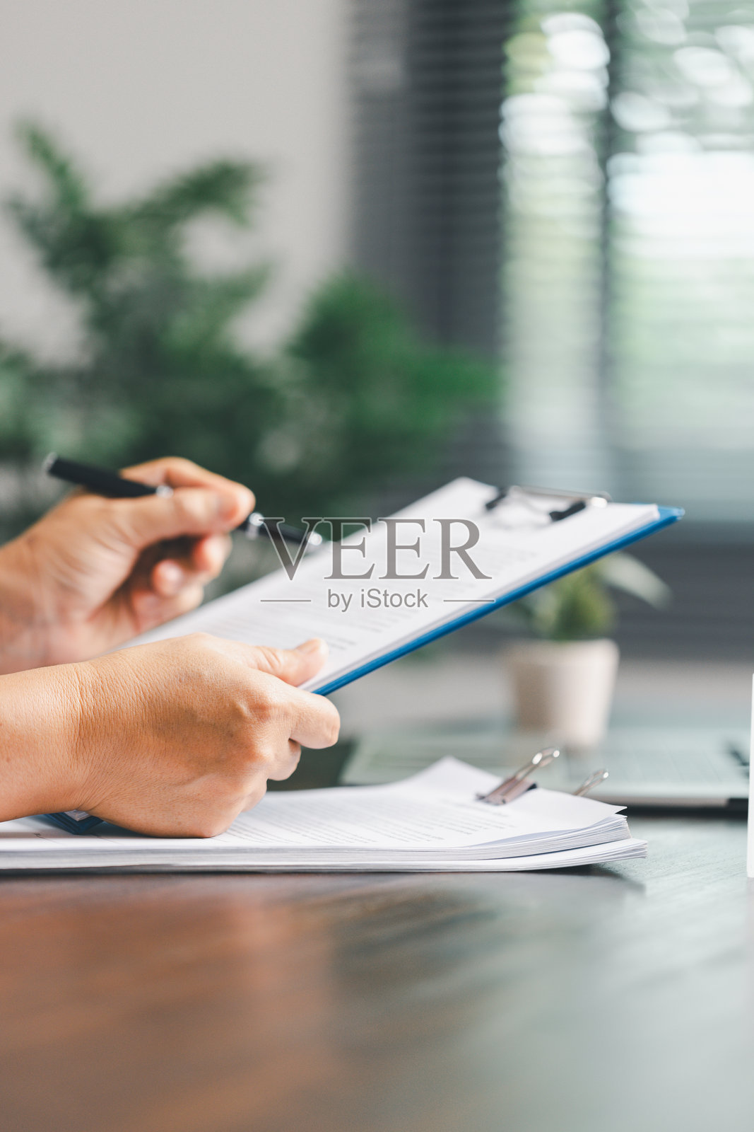 房地产经纪人与客户正在讨论购房合同，背景中有房屋模型，象征着与此过程相关的房地产、保险和贷款安排。照片摄影图片