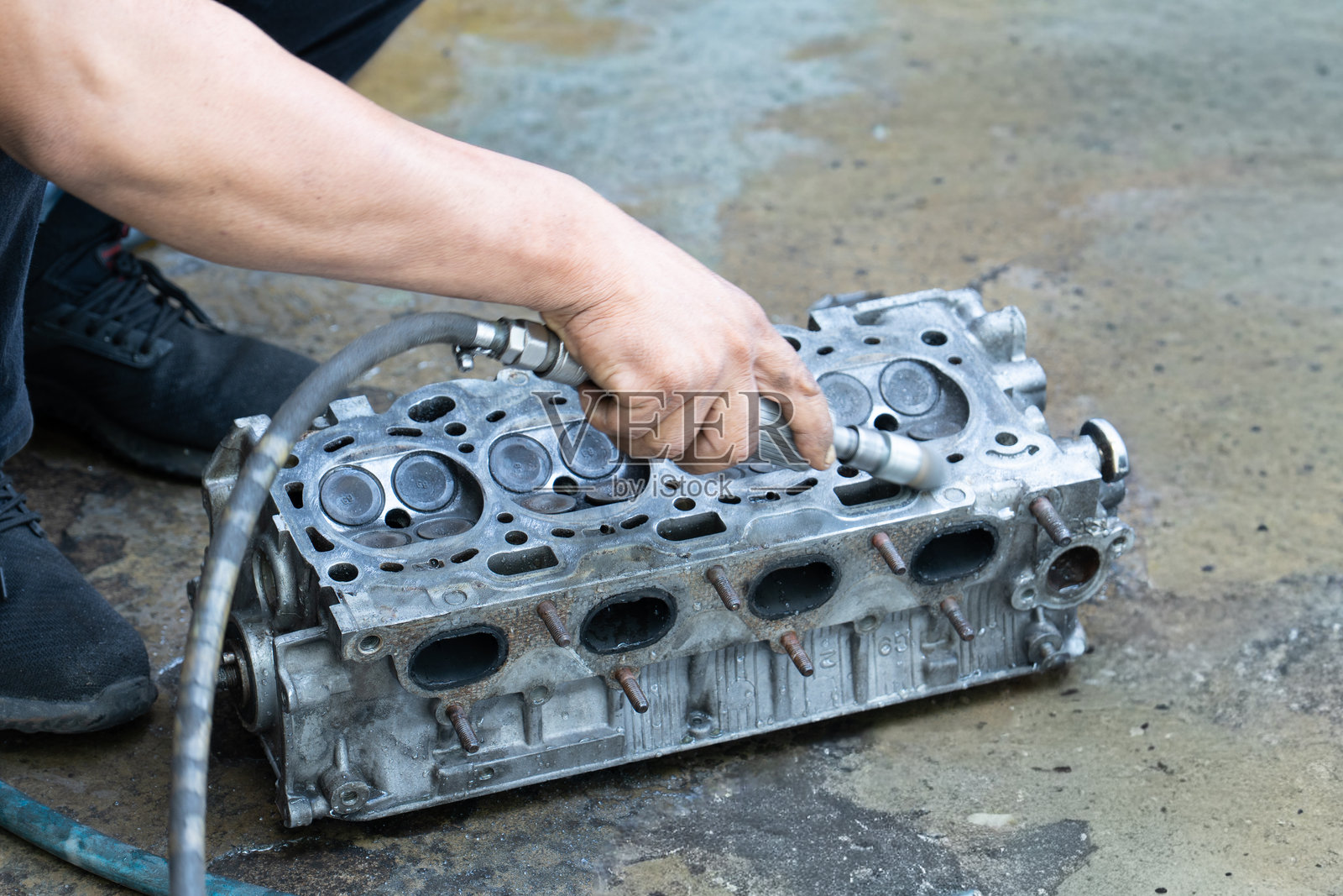 一名机械师的手正在清洁汽车发动机气缸盖。照片摄影图片
