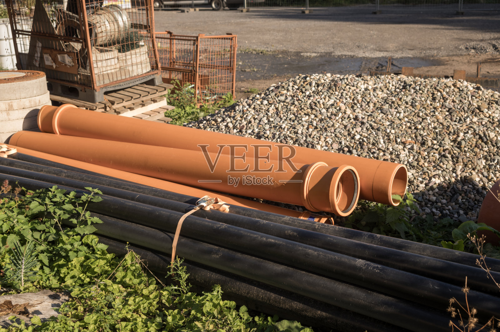 建筑工地上躺着橙色和黑色的塑料管道照片摄影图片