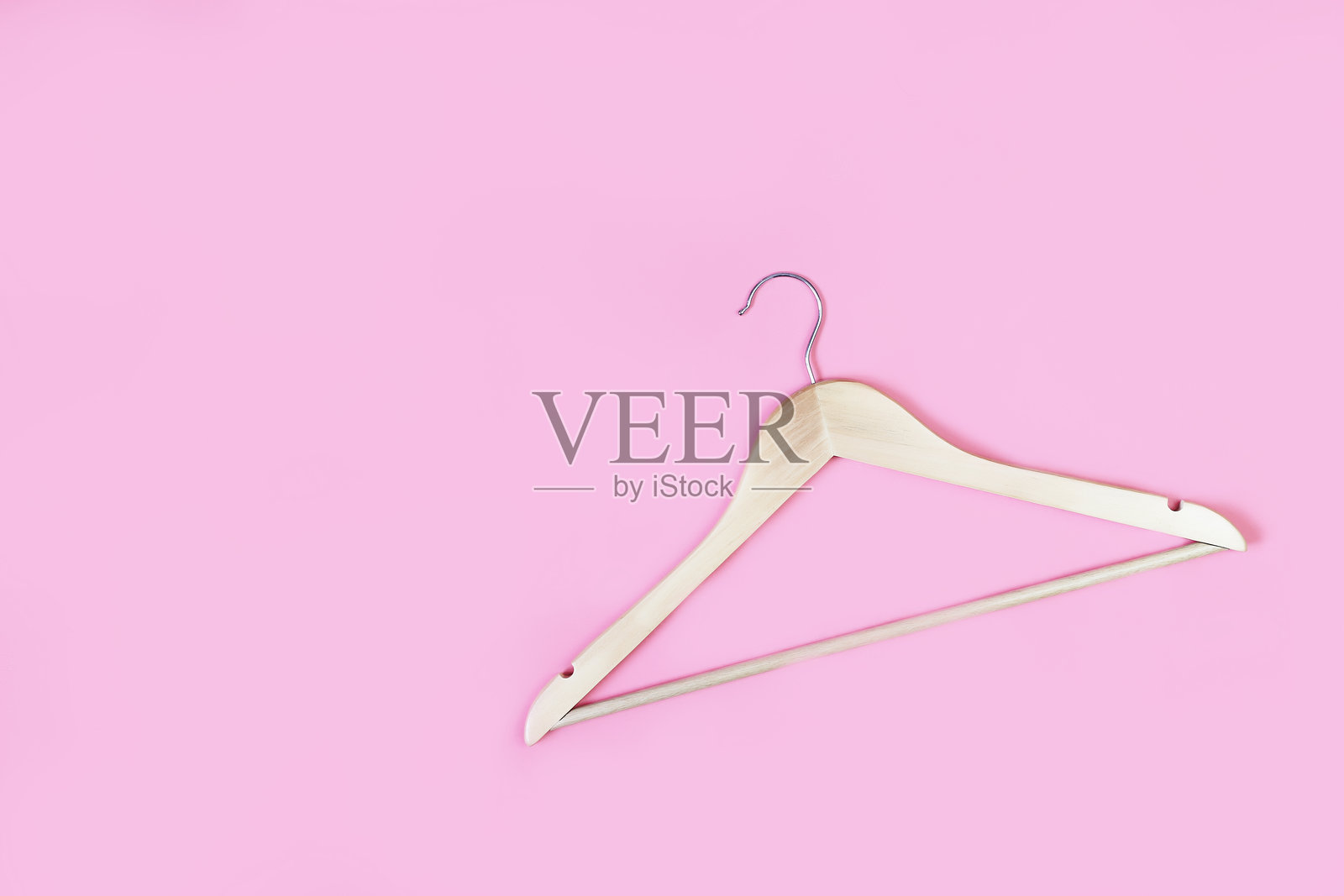 粉色背景上的木质衣架照片摄影图片