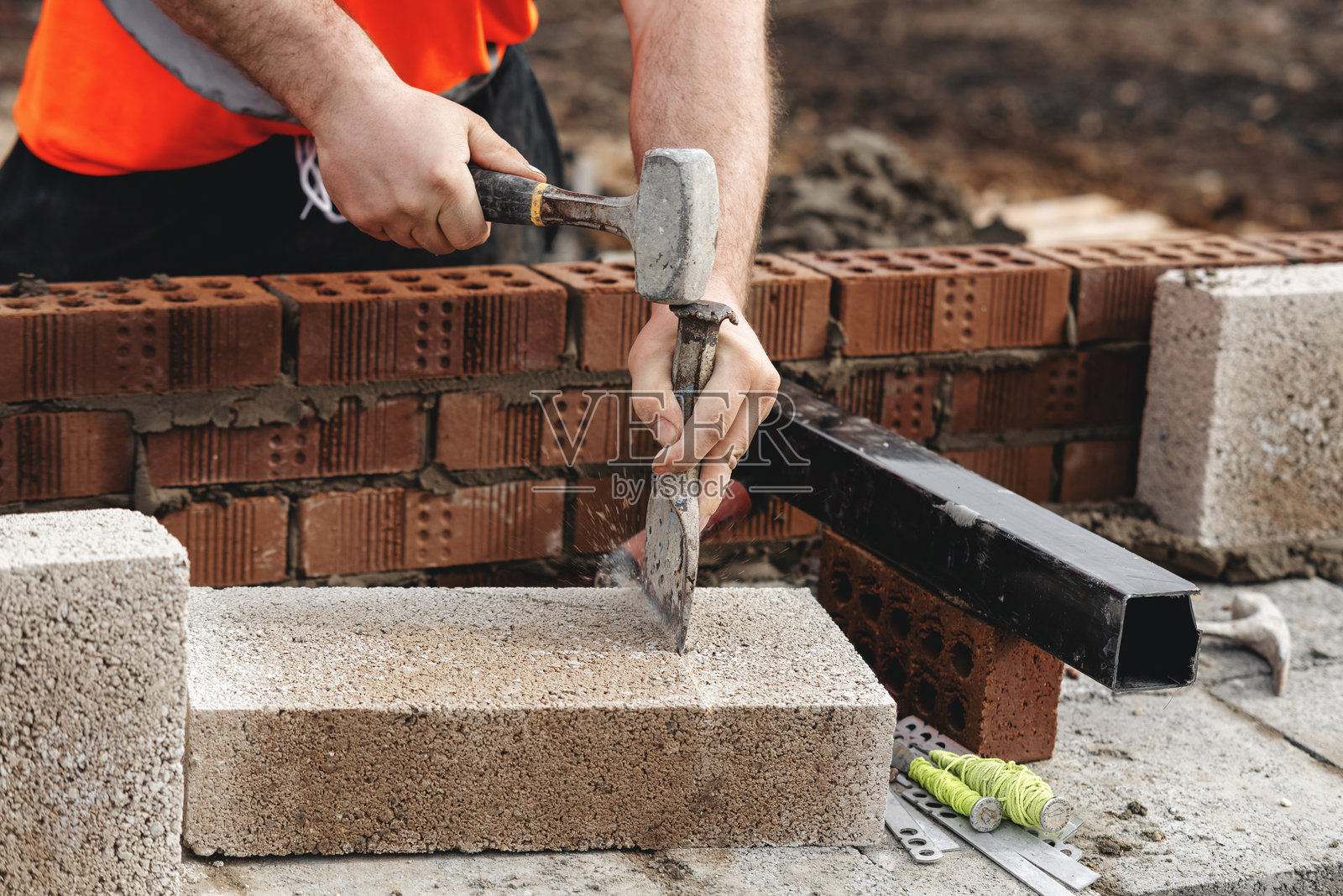 建筑工人在下午阳光下的施工现场砌筑混凝土块以建造墙壁照片摄影图片