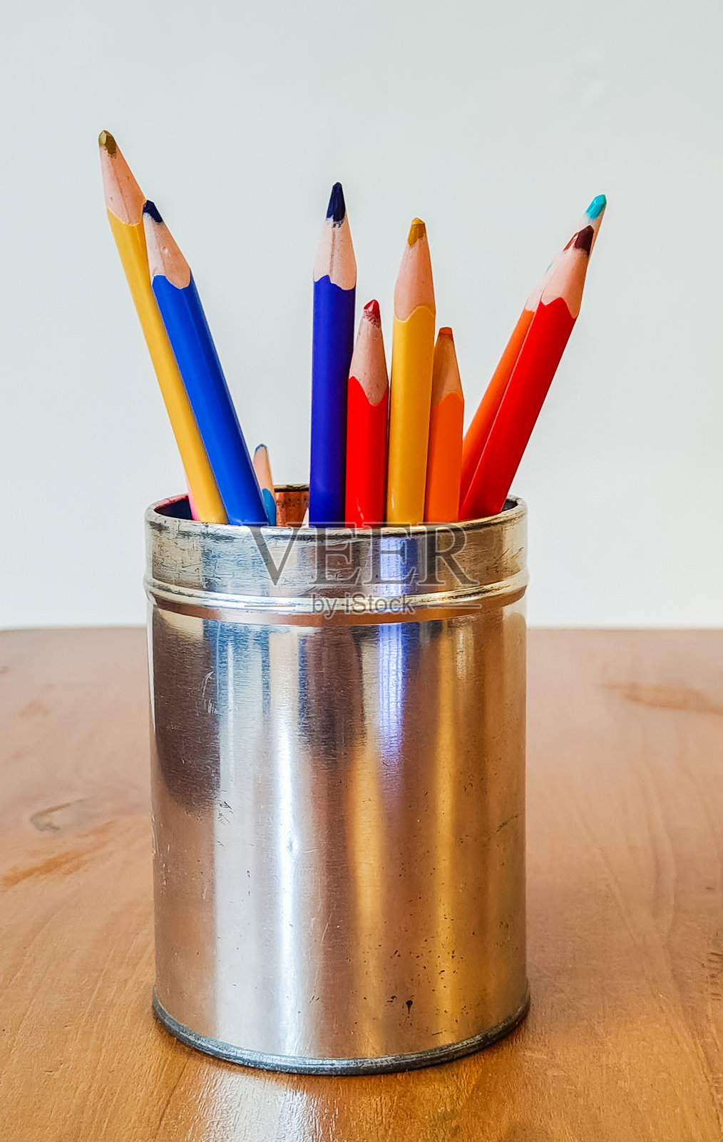 各种颜色的削尖彩色铅笔放在木桌上的铁盒里照片摄影图片