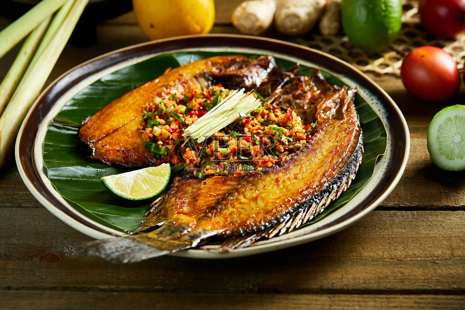 炸鱼和辣椒调料涂抹在叶子上，东南亚美食照片摄影图片