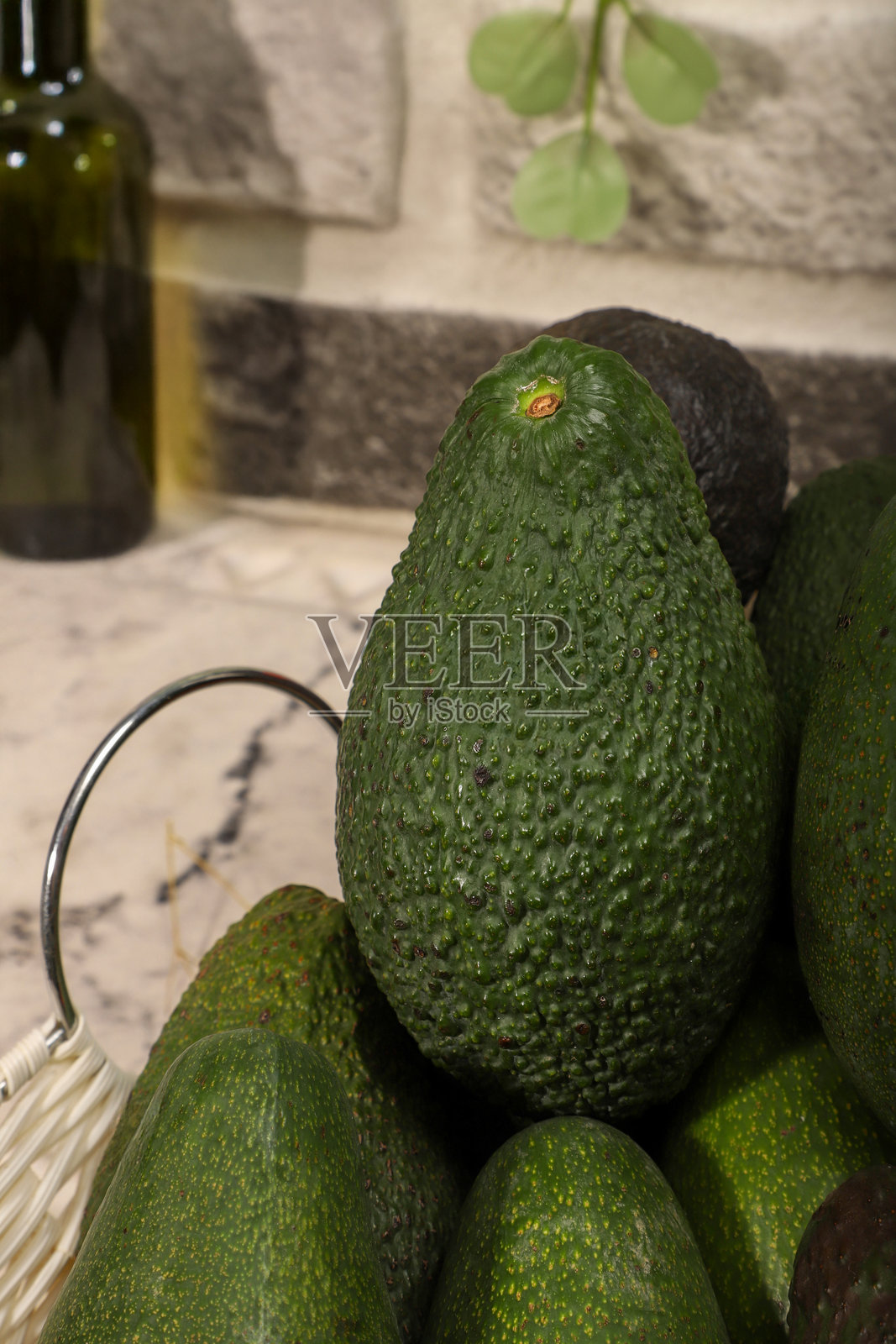 新鲜成熟的鳄梨放在装饰性绿植的篮子里照片摄影图片