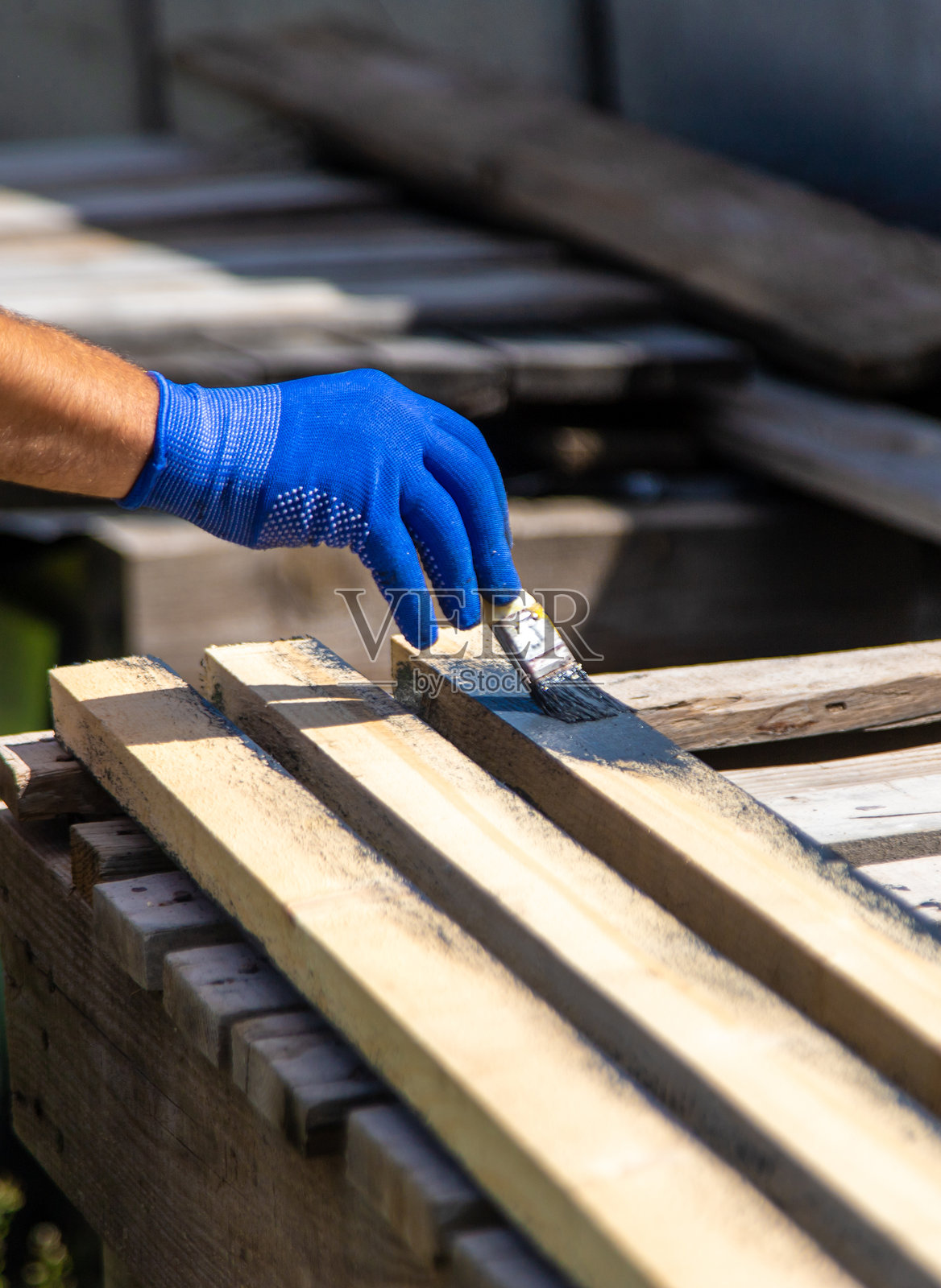 一个男人正在用油漆给木板上色。选择性对焦。照片摄影图片