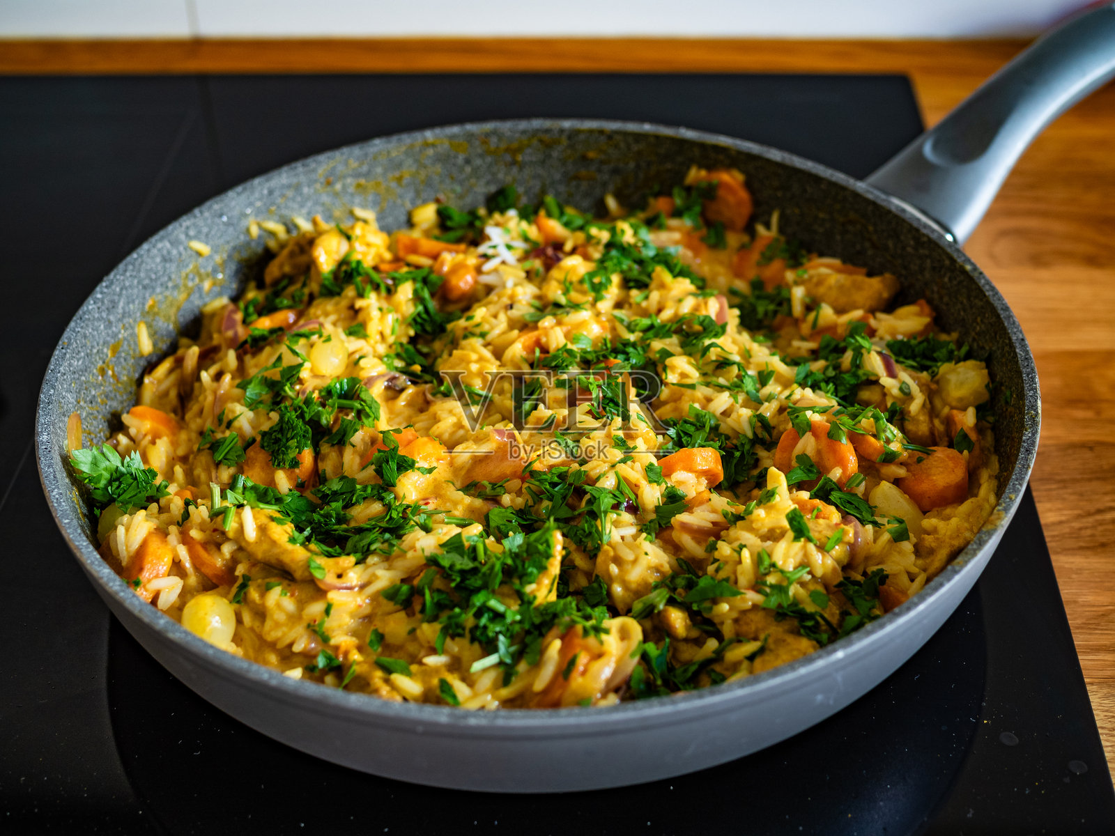 炒锅上的电磁炉上放着鸡肉咖喱、蔬菜和白米饭照片摄影图片