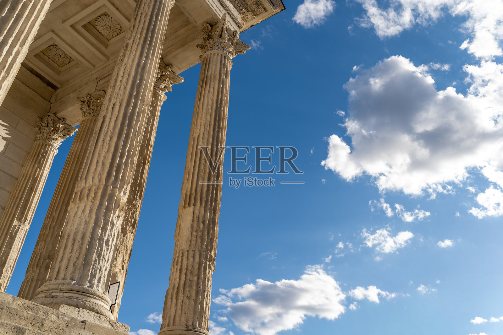 法国尼姆市中心的卡尔雷宫（Maison Carrée）罗马神庙的石柱，背景是夏日的天空。照片摄影图片