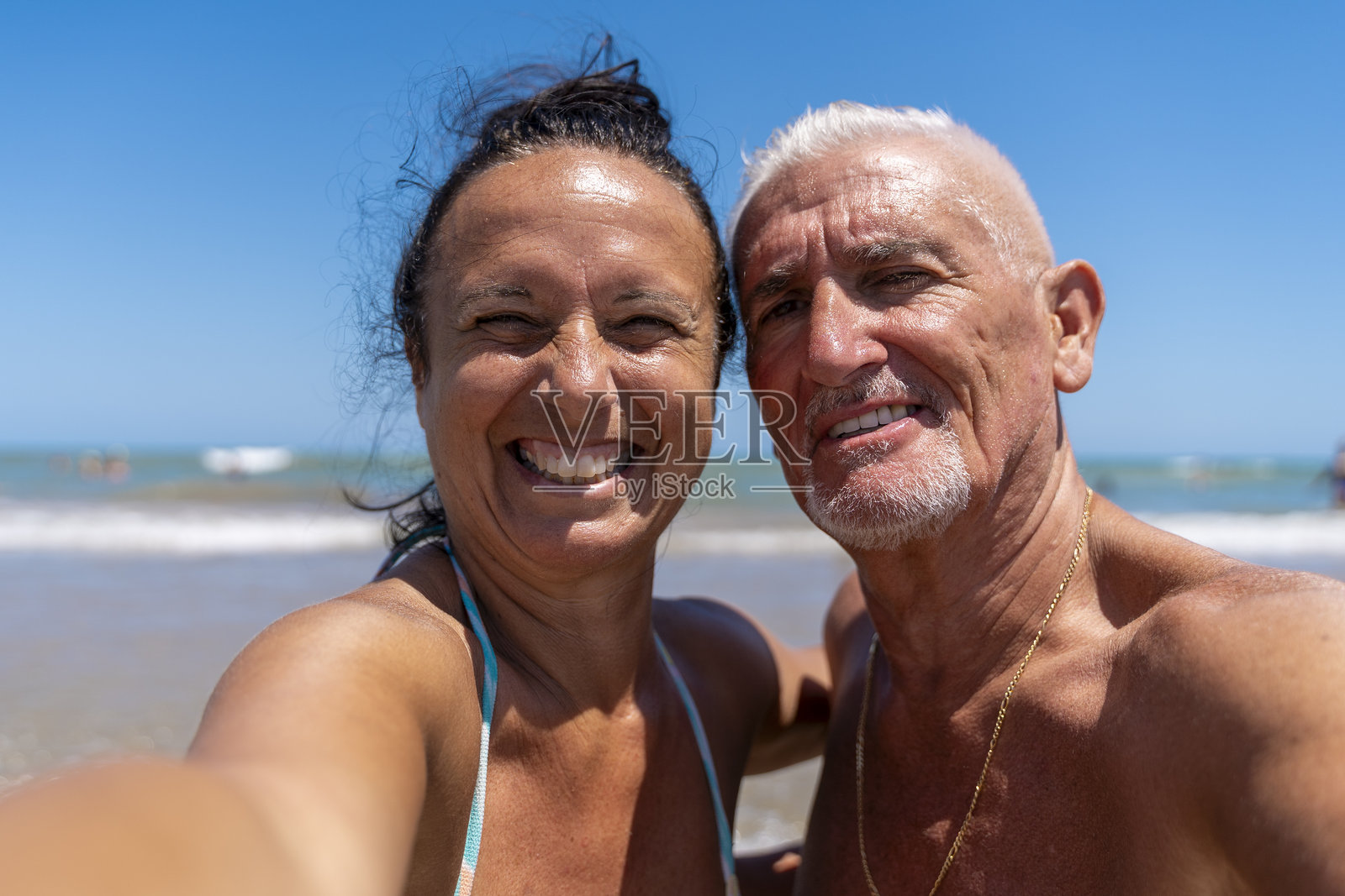 一对年轻快乐美丽的退休夫妇在海滩上拥抱着彼此，拍摄自拍照，享受夏季假期。照片摄影图片