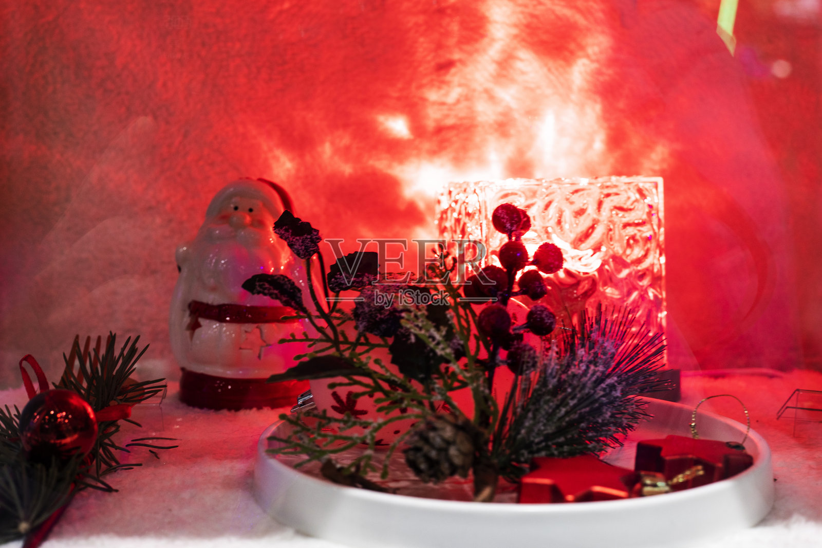圣诞老人雕像被红色灯光照亮，周围装饰着圣诞装饰品照片摄影图片