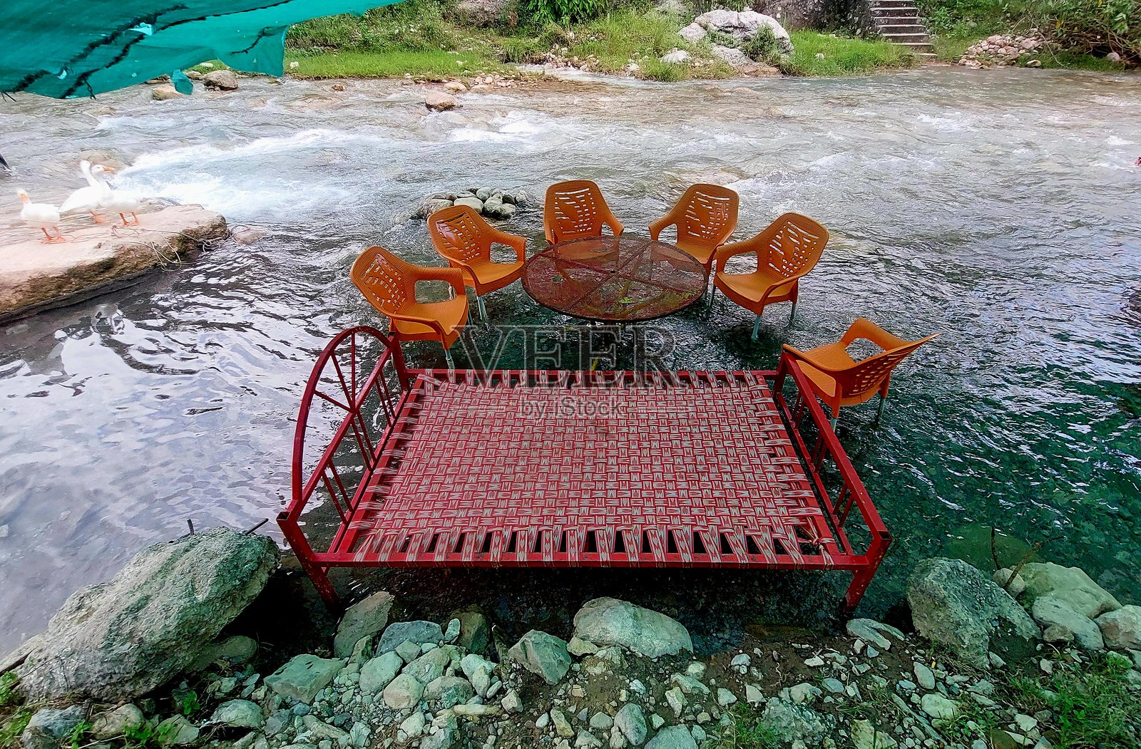 河边休息区，配有草席床和塑料椅子，旁边有自然溪流照片摄影图片