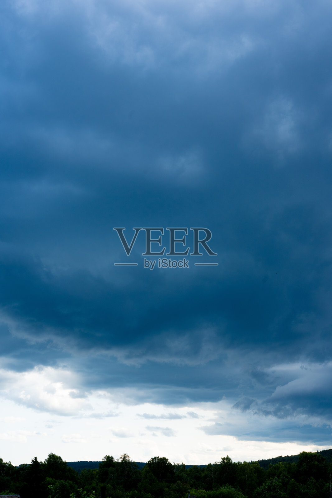 戏剧性的云景：在动荡的天空下，黑暗的暴风云在起伏的山丘上聚集，形成迷人的景观。照片摄影图片