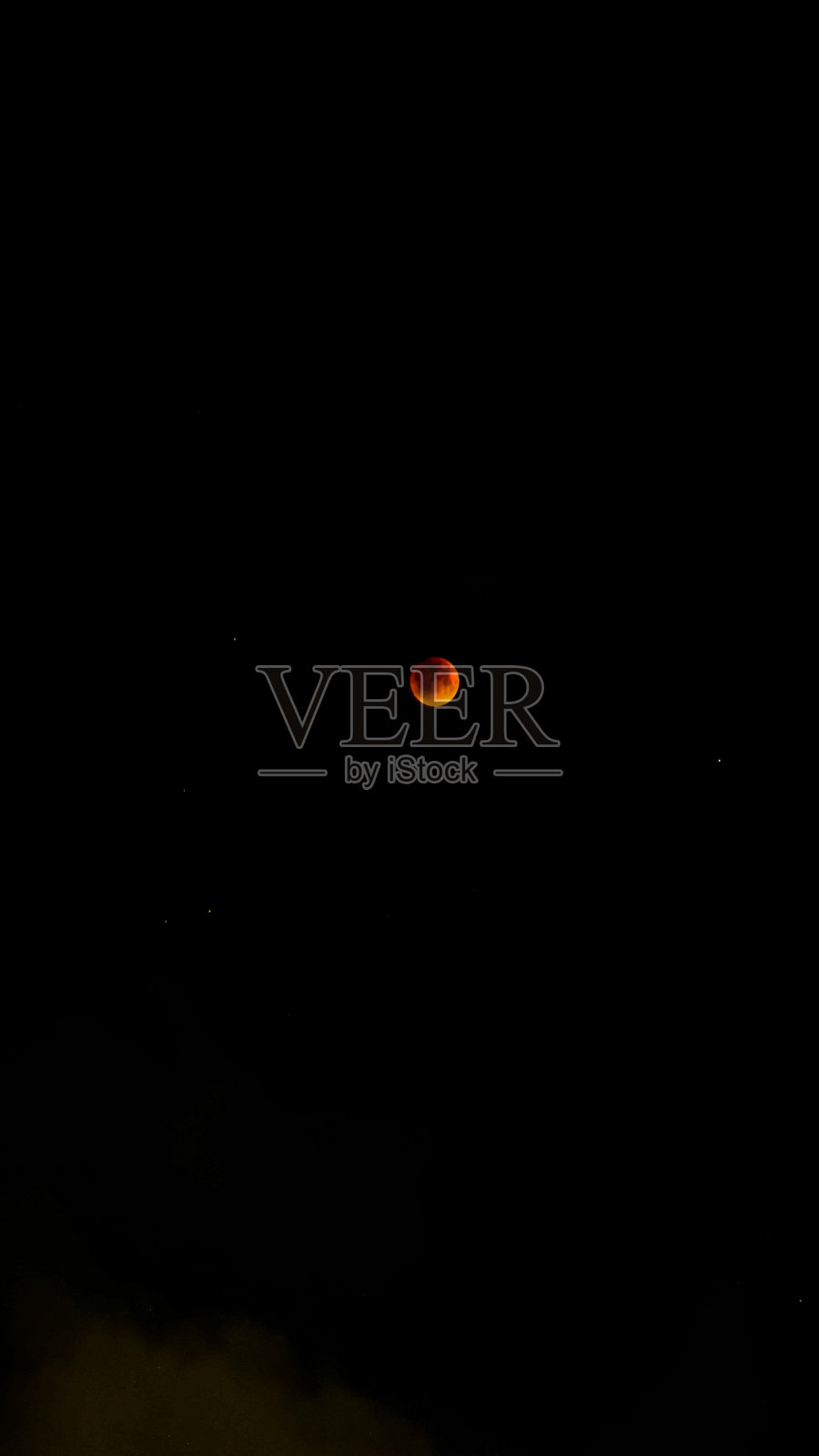 印度的月食壮丽景观，月亮在戏剧性的红色光辉中，周围是星星点点的黑夜和飘动的云朵。照片摄影图片