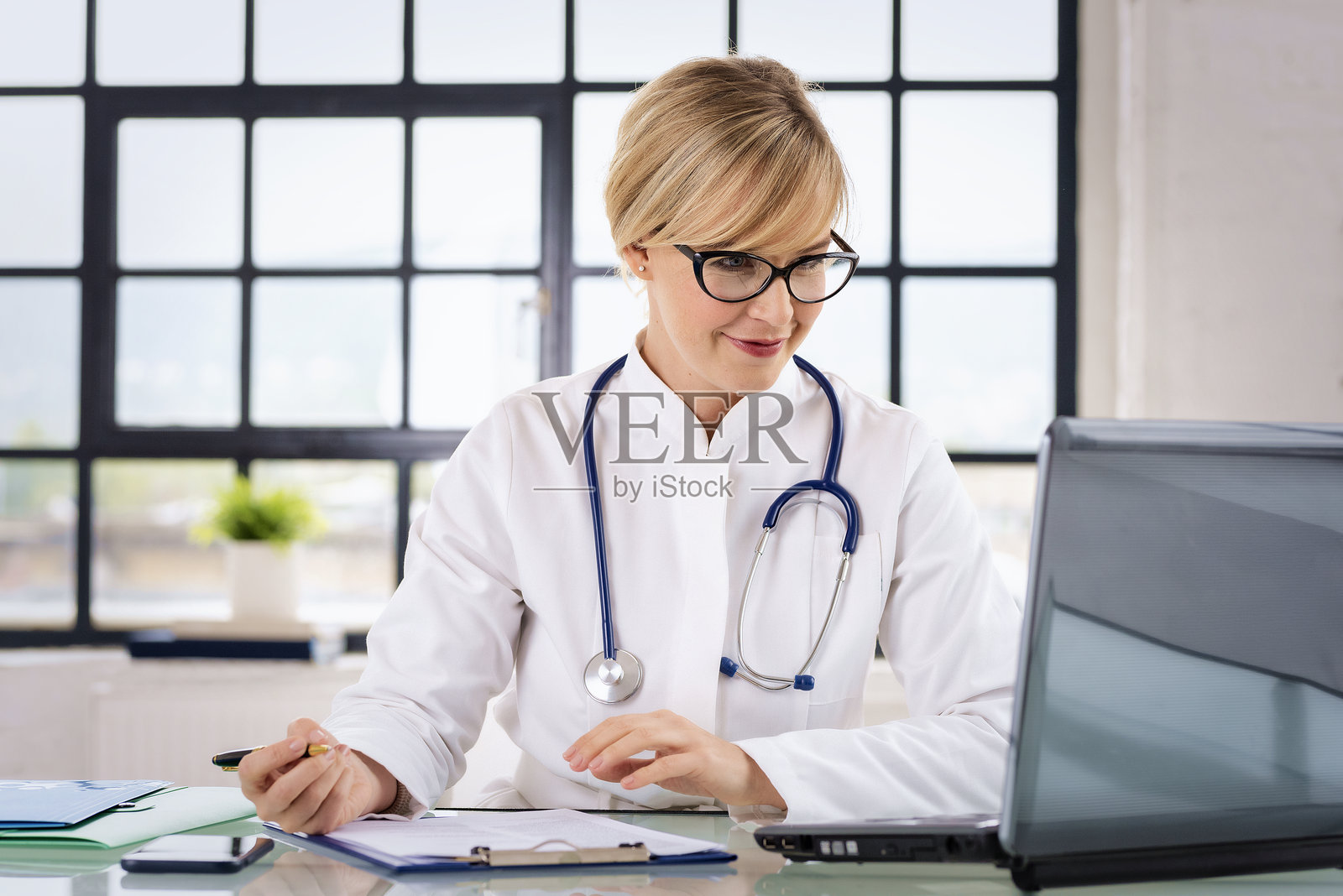 微笑的女医生在办公室使用笔记本电脑工作照片摄影图片