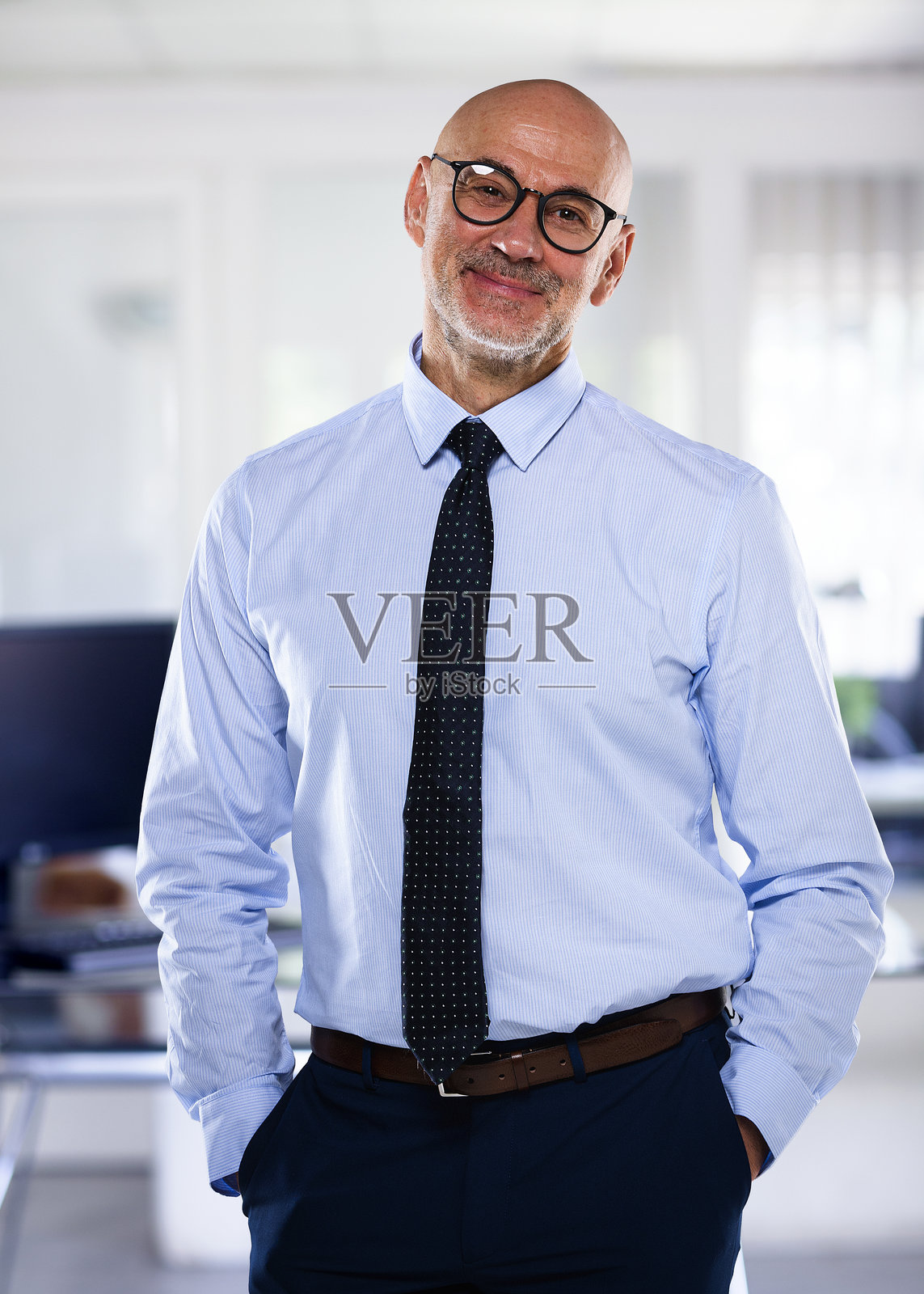 自信的中年商人穿着西装，站在办公室里照片摄影图片