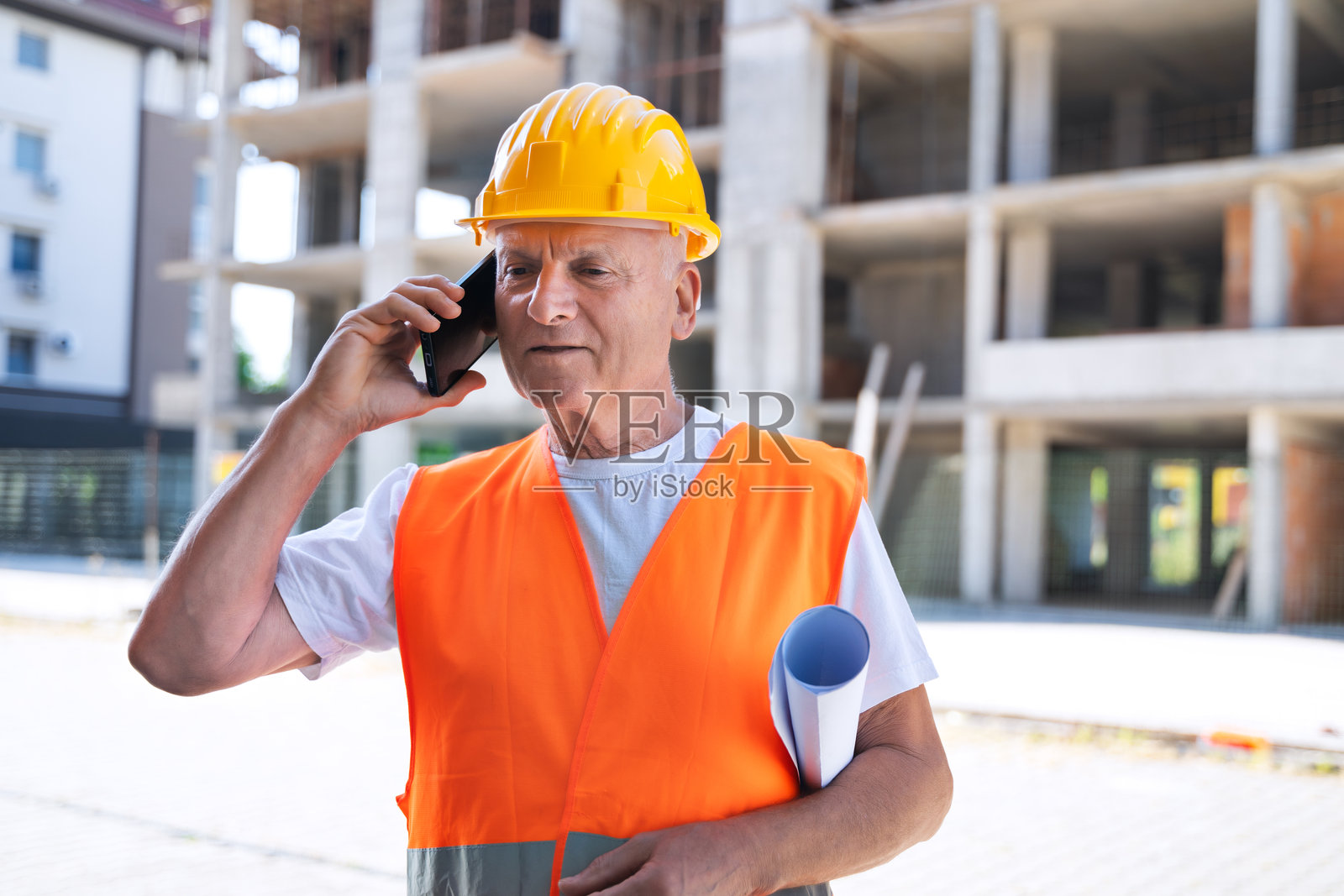 建筑工地上的高级工人正在打电话照片摄影图片