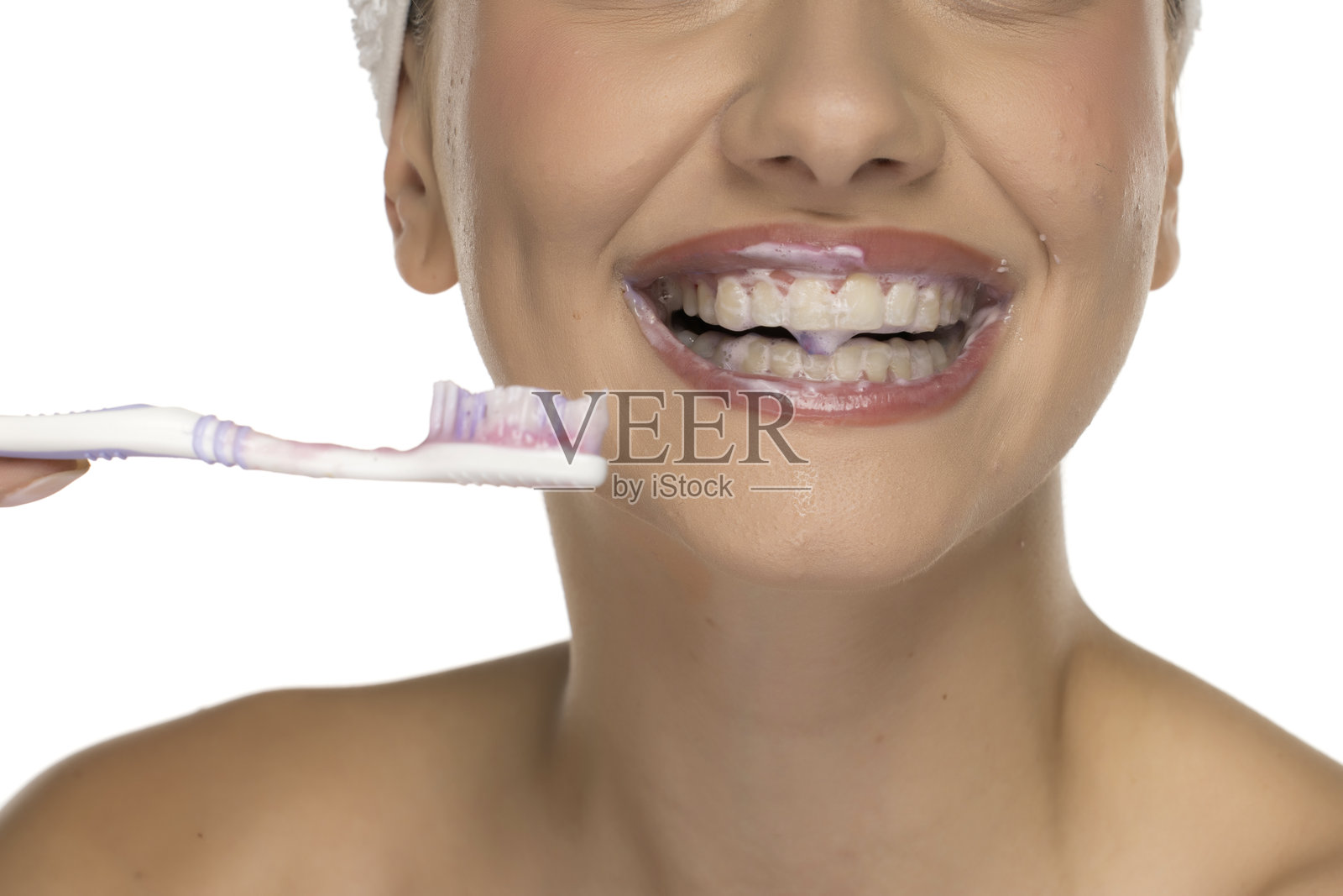 特写镜头：女性嘴唇上有牙膏泡沫，手持牙刷，白色背景下的摄影作品。照片摄影图片