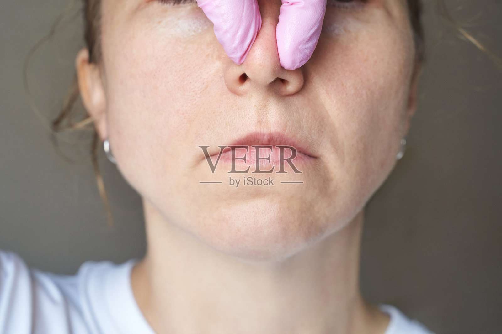 女性白人成人正在接受鼻部检查，医生戴着粉色医用手套。照片摄影图片