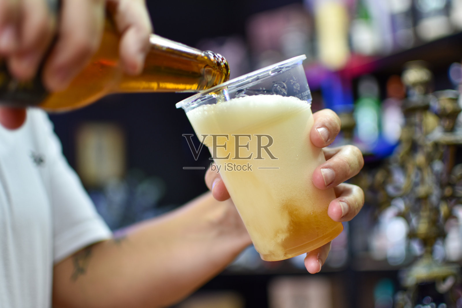 一位女性正在将啤酒倒入玻璃杯中。照片摄影图片