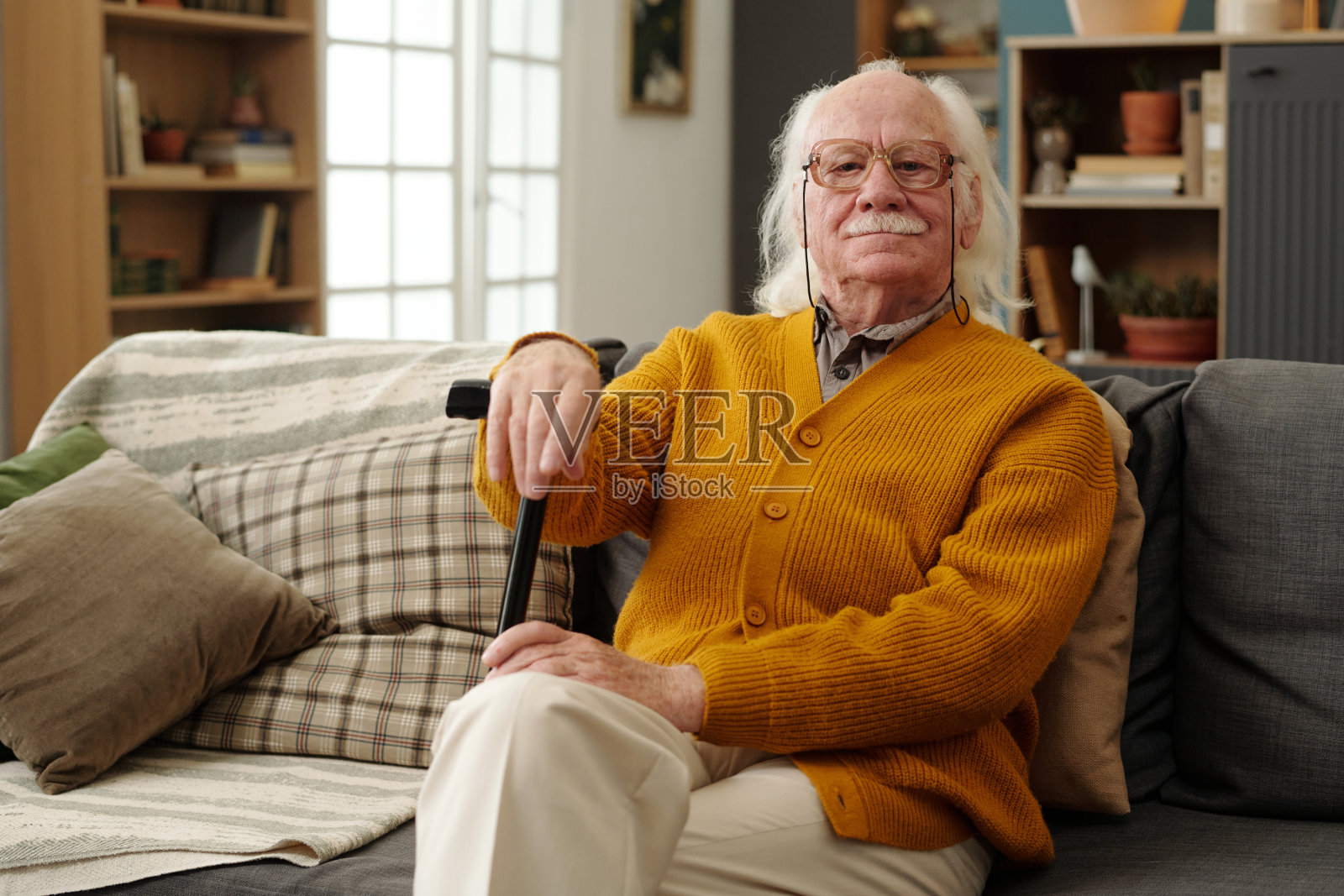 坐在沙发上，手持拐杖的自信老年白人男性肖像照片摄影图片