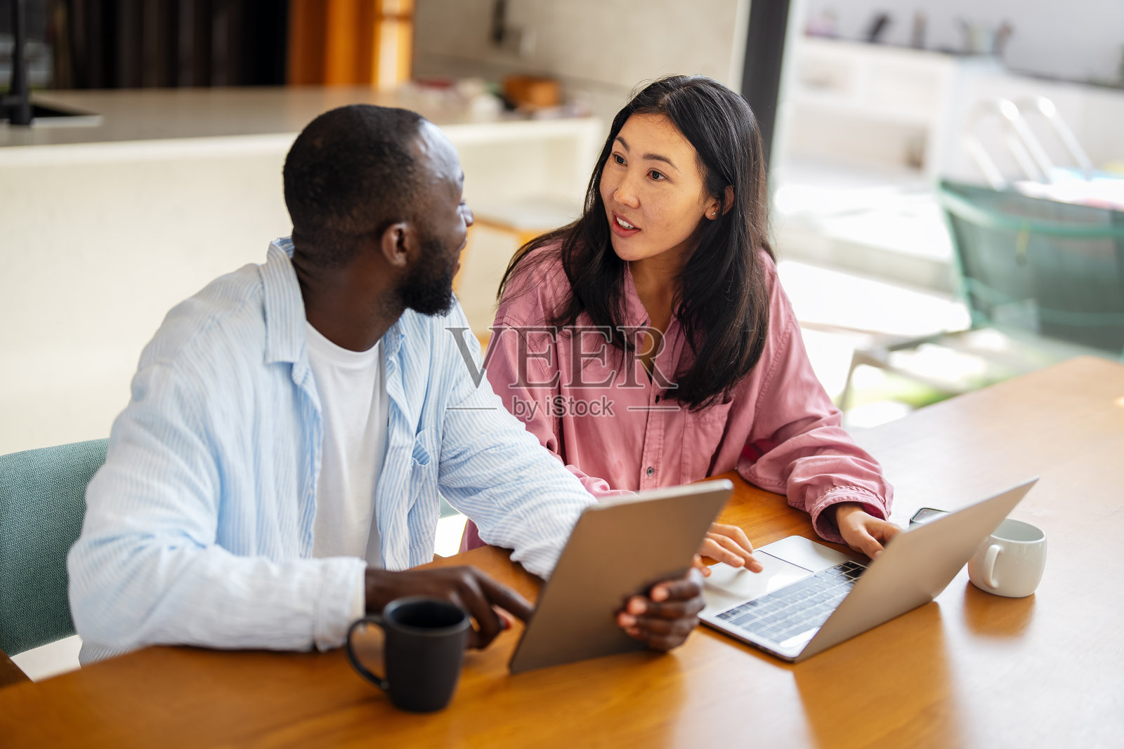 多民族自由职业者情侣在热带气候的环境中一起享受工作，使用笔记本电脑。照片摄影图片