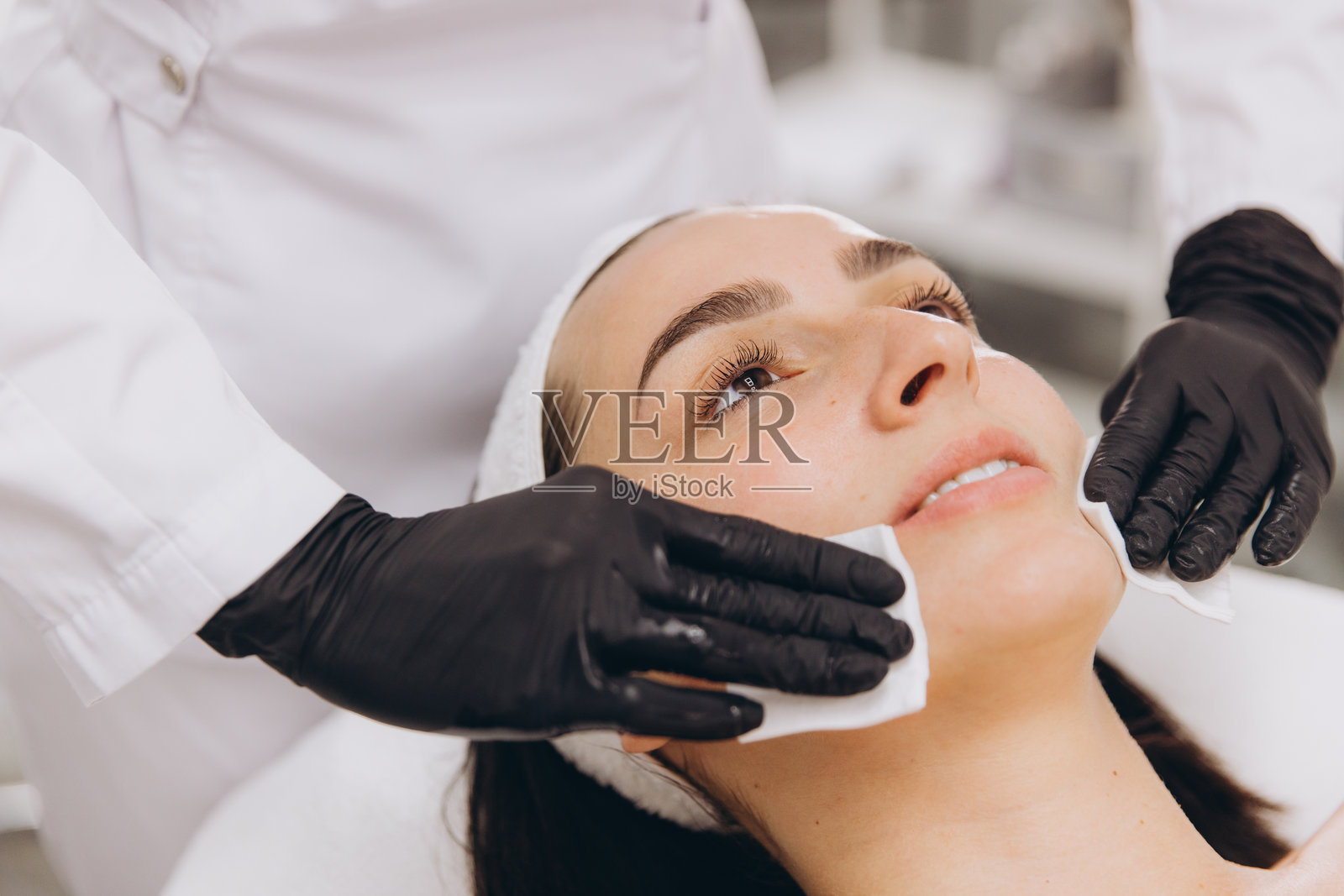 美容师正在为女性使用卸妆湿巾。照片摄影图片