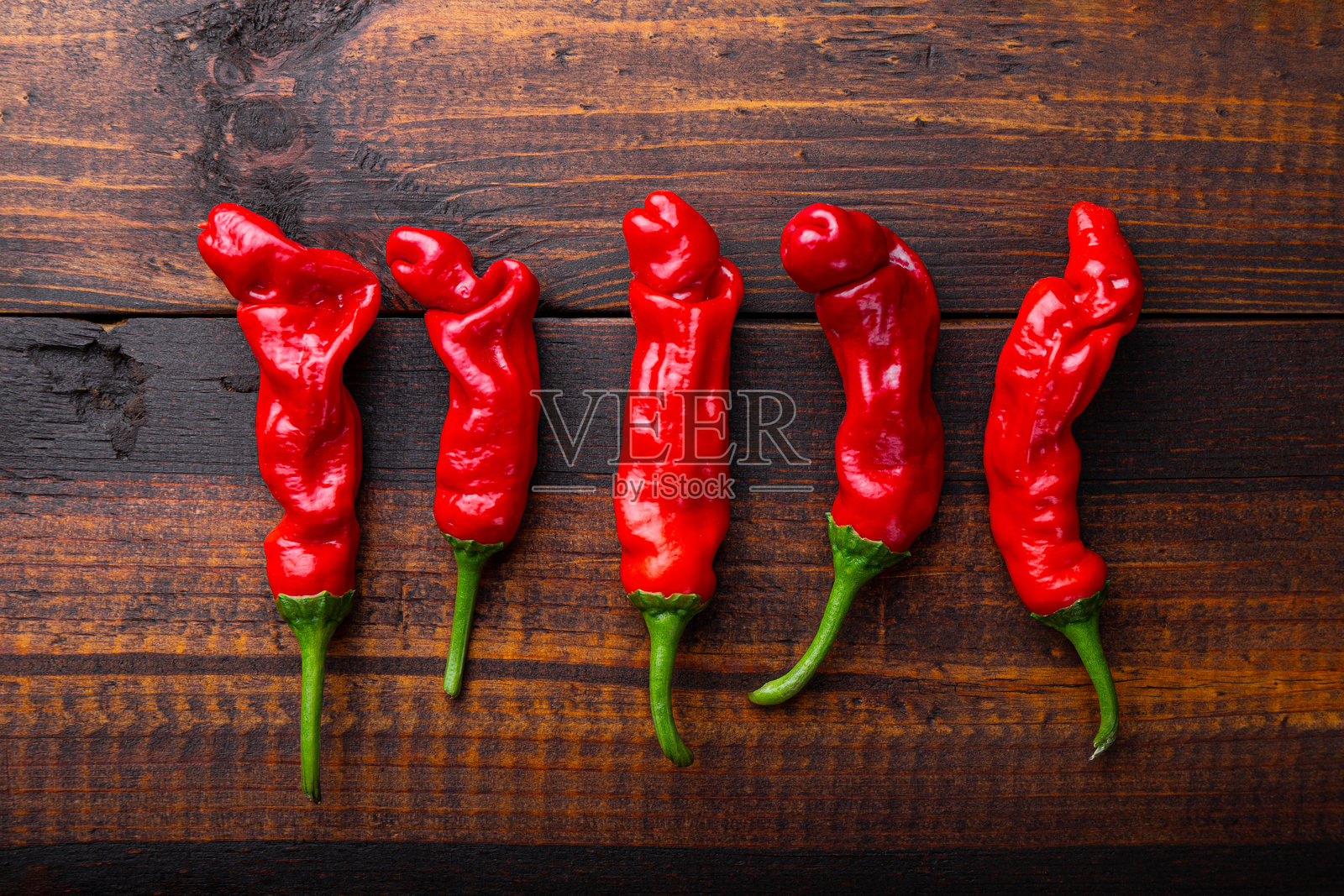 成熟的辣椒呈阴茎形状，彼得辣椒在木质背景上照片摄影图片