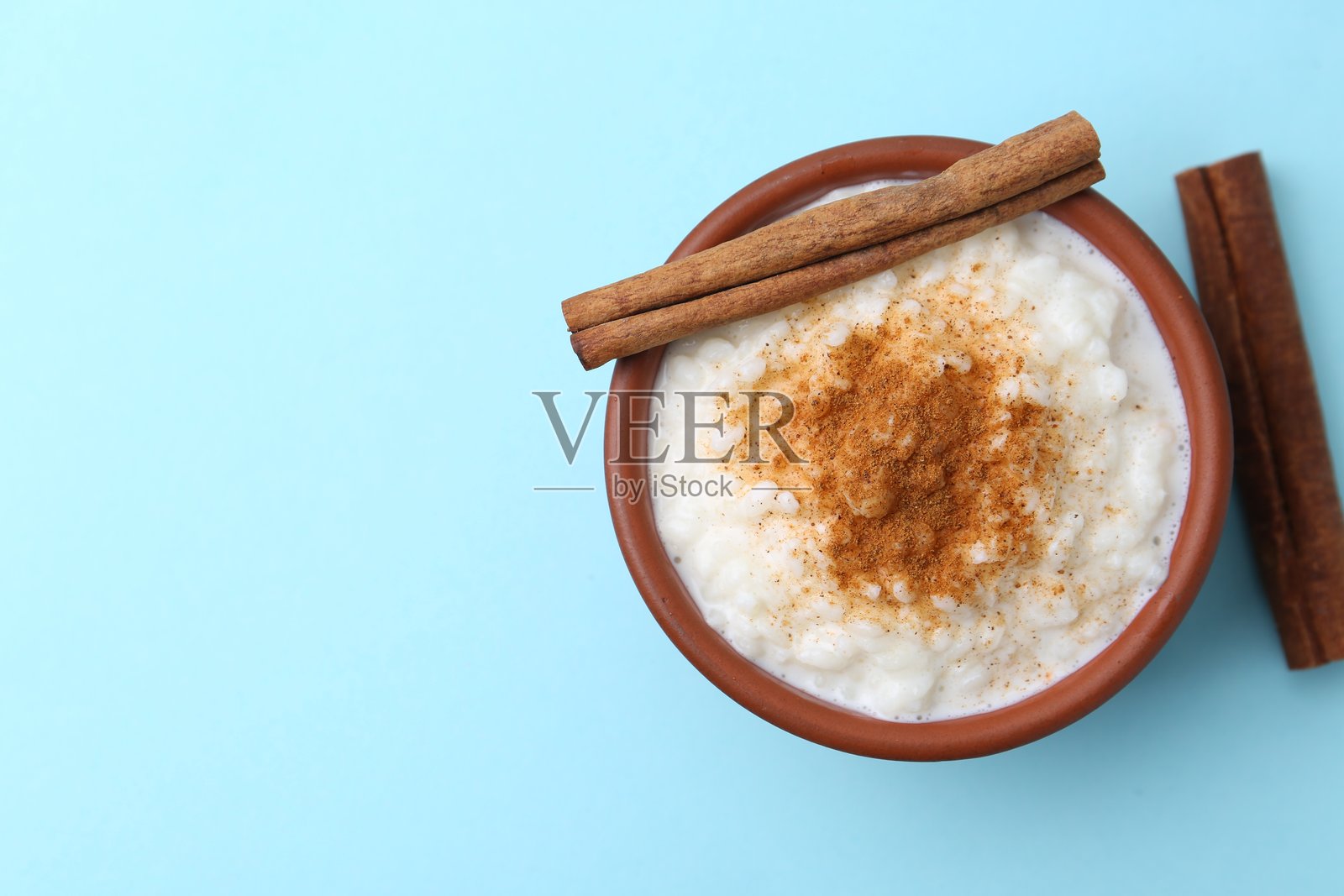 美味的米布丁配肉桂棒，背景为浅蓝色，俯视图。留有文字空间。照片摄影图片